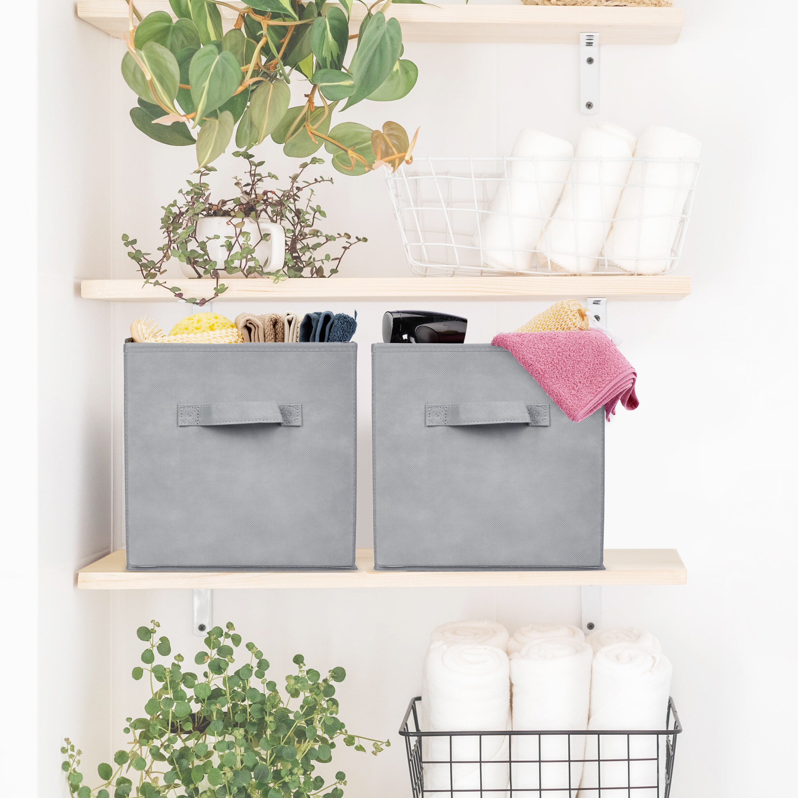 Wunderschönes Holzregal mit grauen Aufbewahrungsboxen, weißen Handtüchern und grünen Pflanzen für eine ordentliche Bad-Organisation.