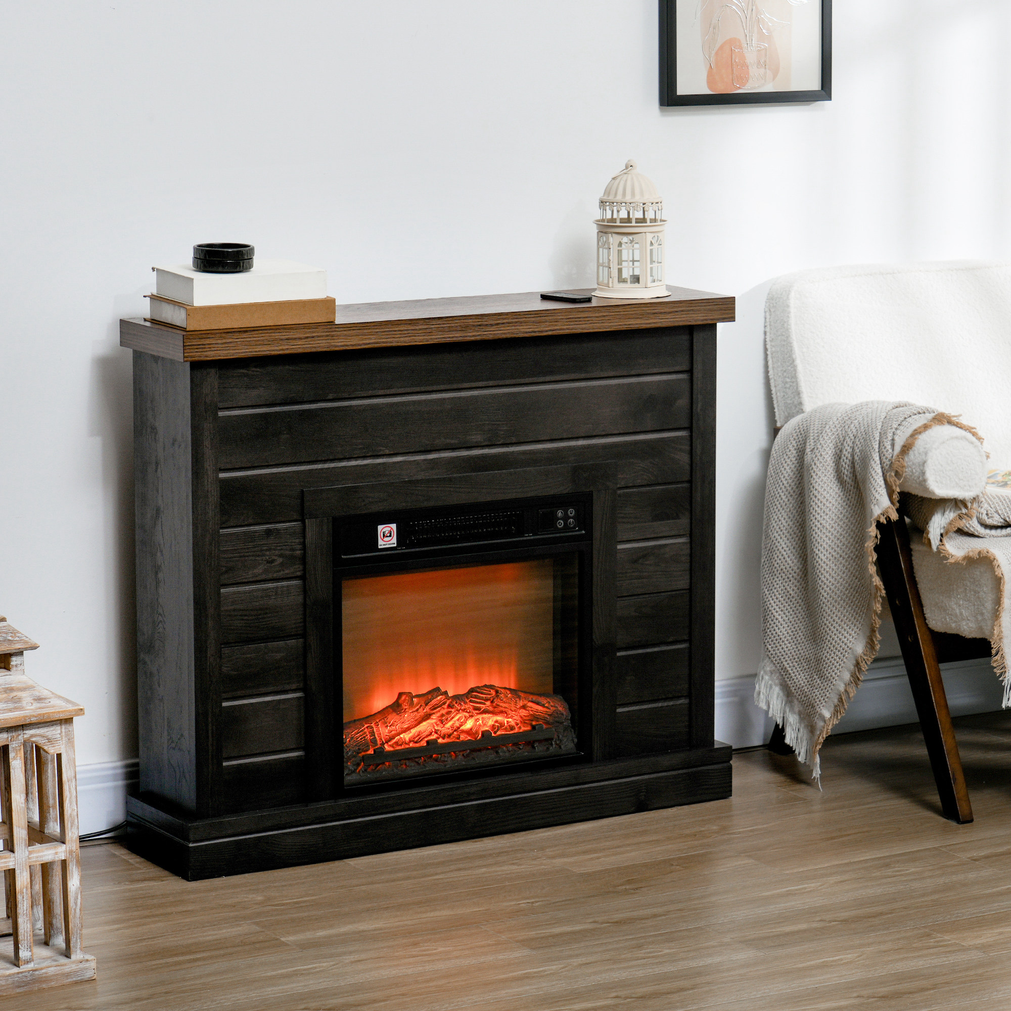 Una chimenea eléctrica de madera oscura se encuentra contra una pared blanca al lado de un sillón.