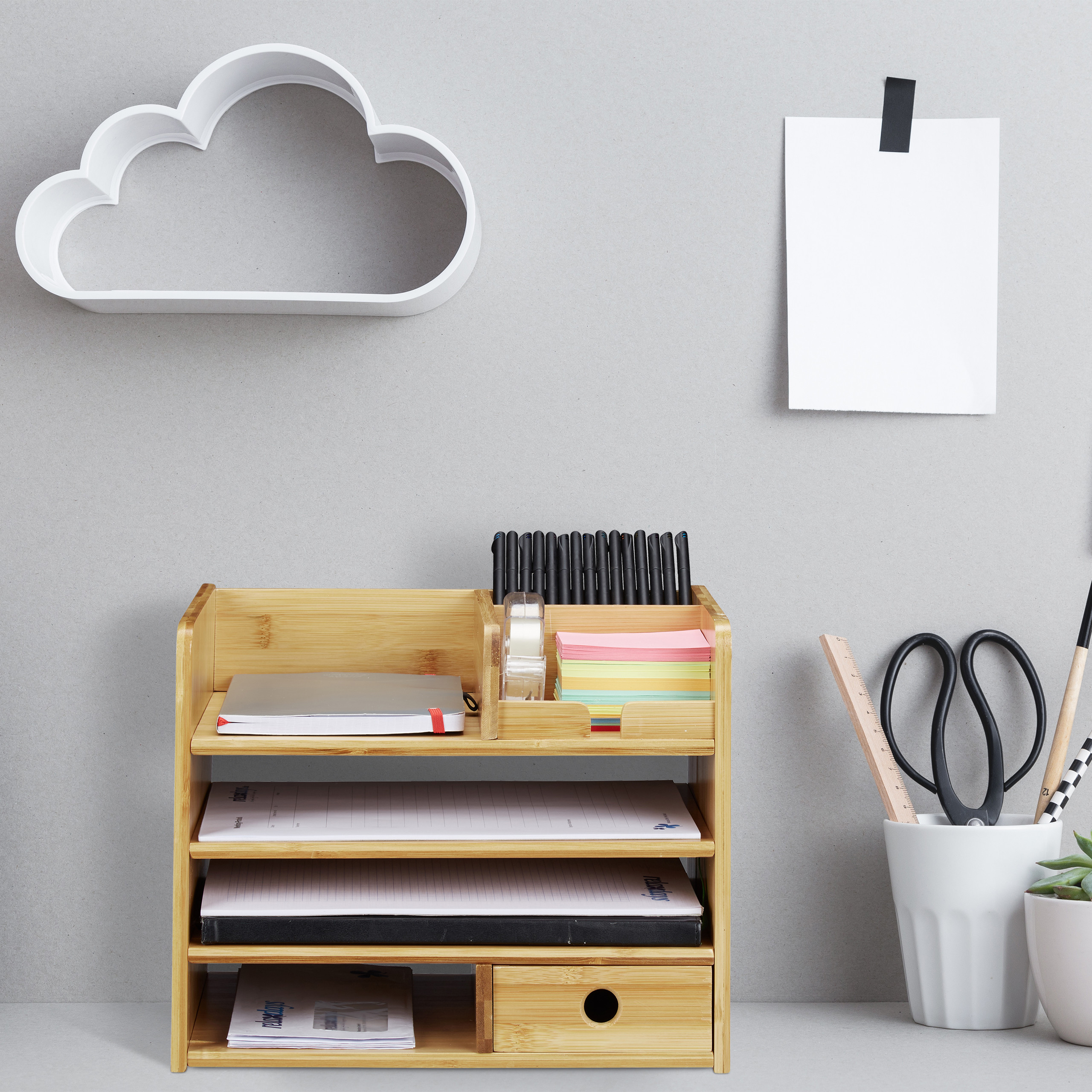 Bambus-Schreibtisch-Organizer mit Notizbüchern, Stiften und Zubehör auf grauem Hintergrund.
