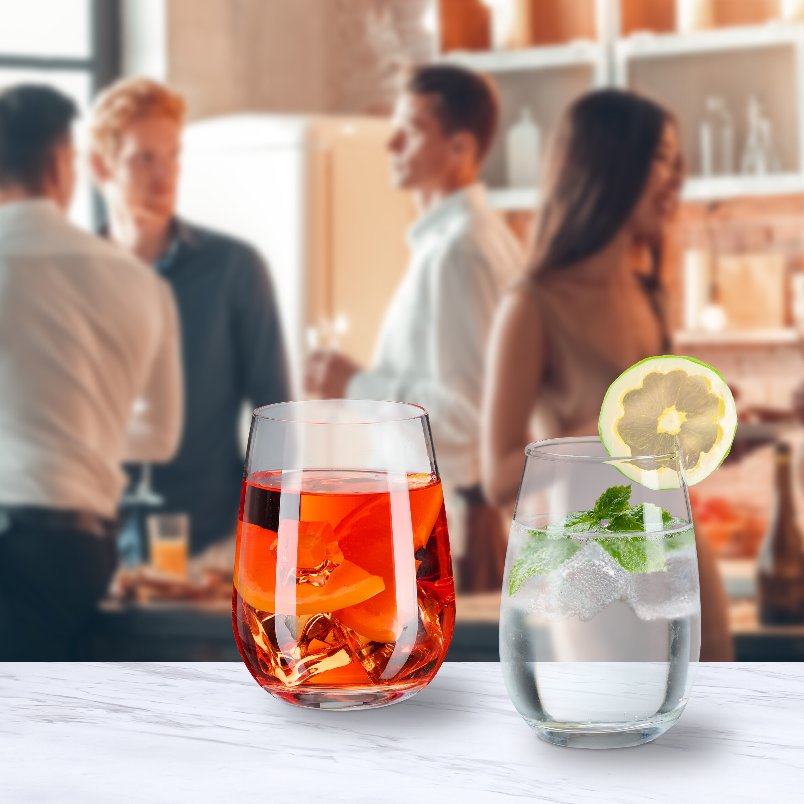 Zwei Cocktails auf einem Tisch, im Hintergrund feiert eine unscharfe Gruppe.