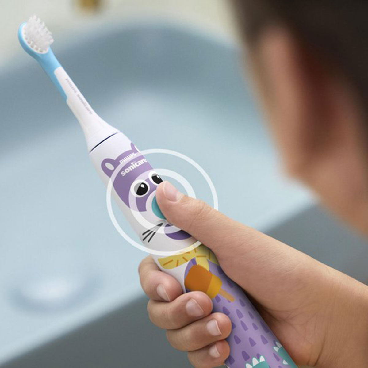 Dziecko trzyma fioletowo-białą szczoteczkę elektryczną Philips Sonicare, naciskając przycisk zasilania.