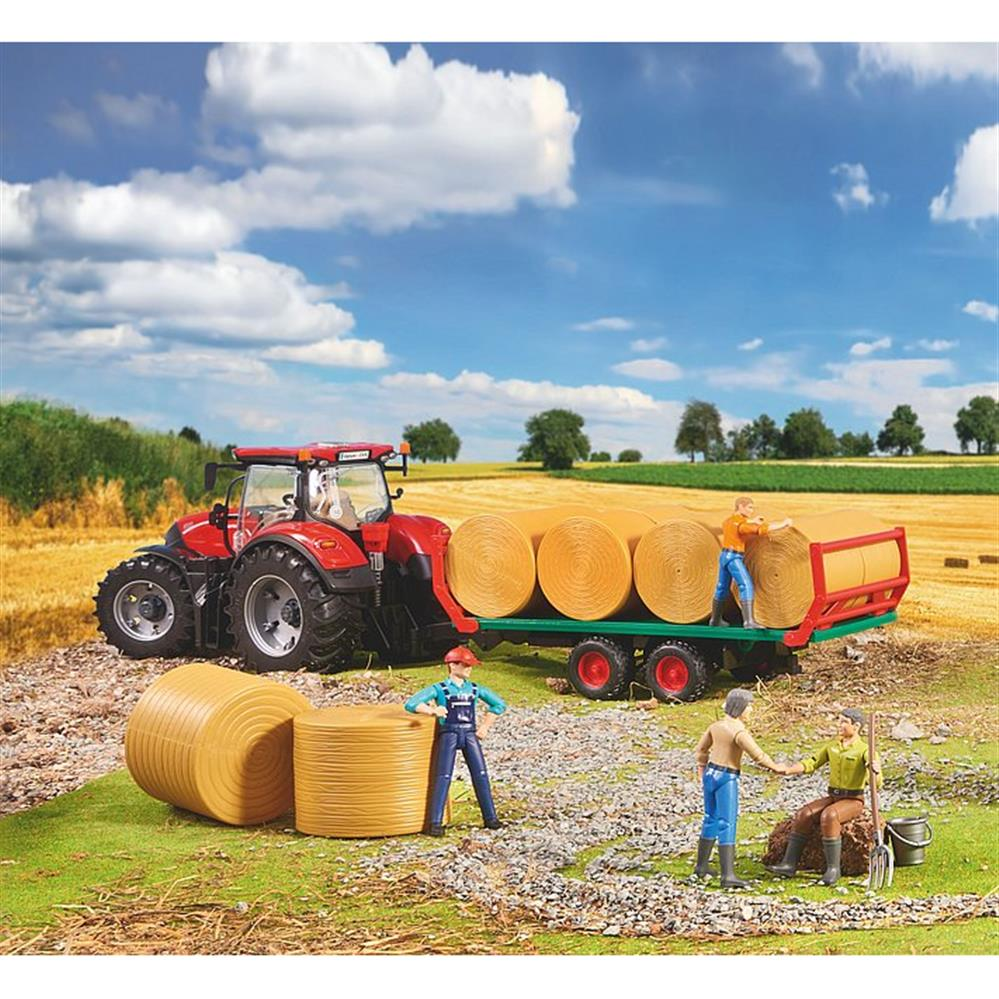 Spielzeugtraktor mit Anhänger, Heuballen und Figuren in ländlicher Landschaft.