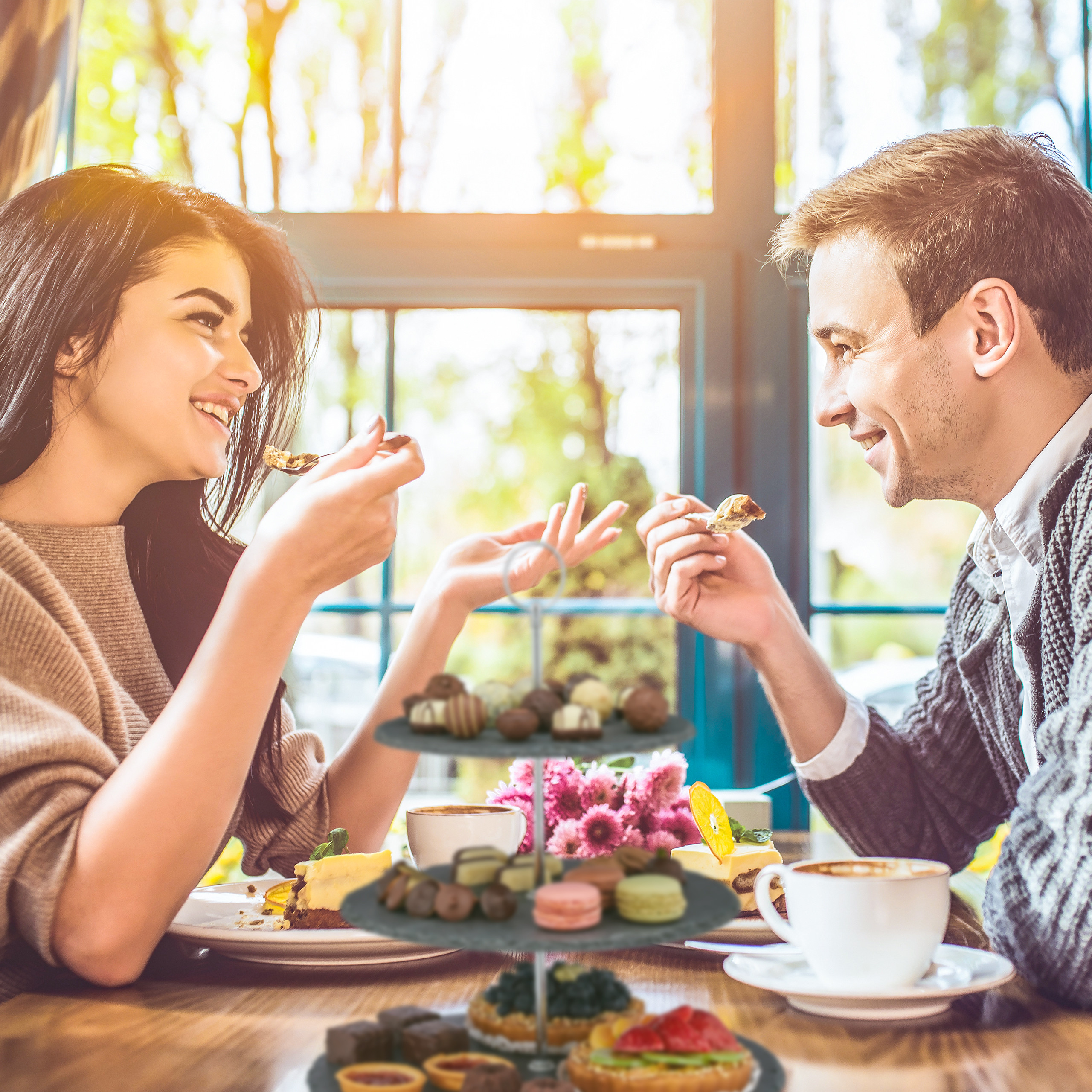 Ein glückliches Paar sitzt in einem Café, genießt Kaffee und Gebäck und lächelt sich an.