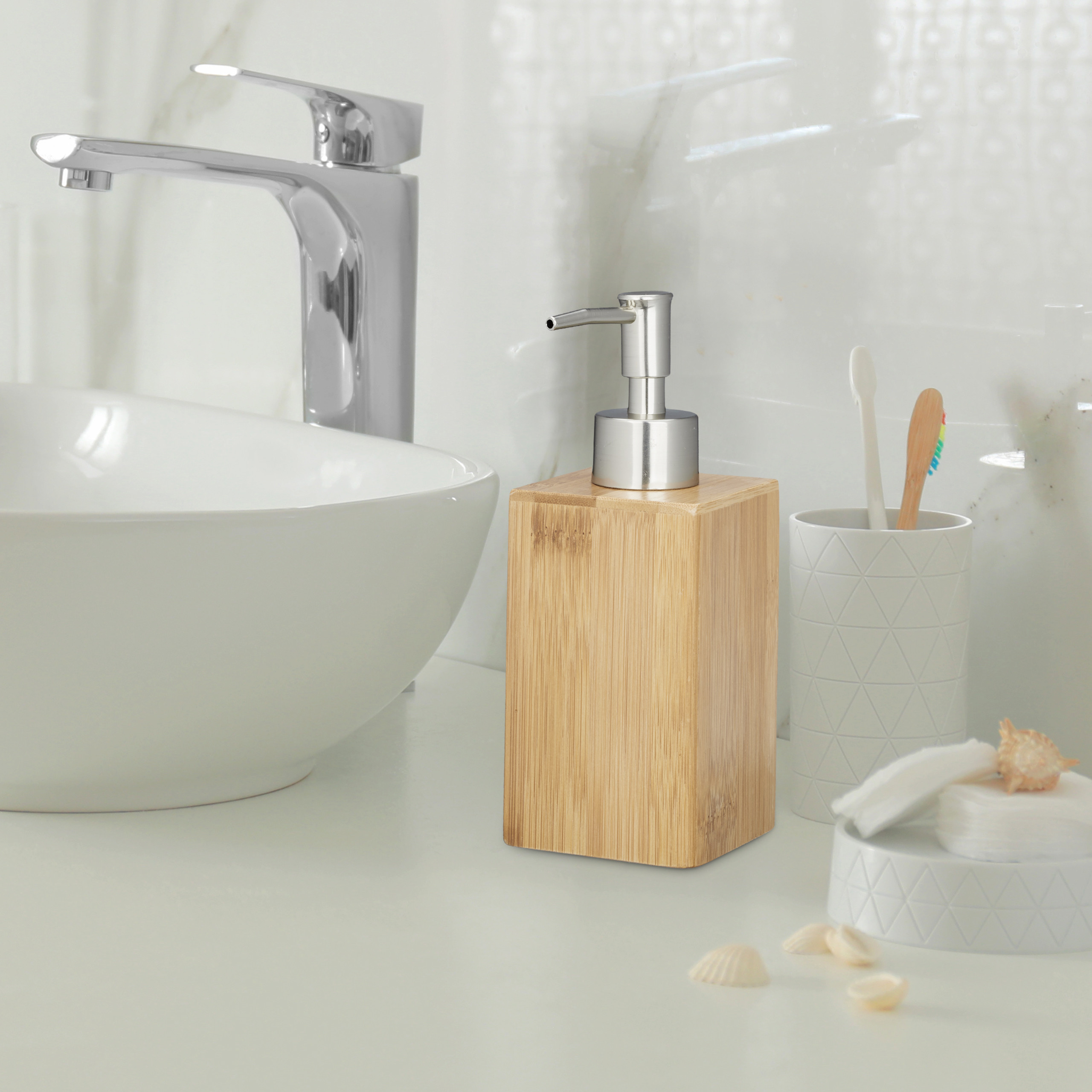 Seifenspender aus Holz mit Edelstahlpumpe auf einem Waschtisch neben Waschbecken und Zahnputzbecher.