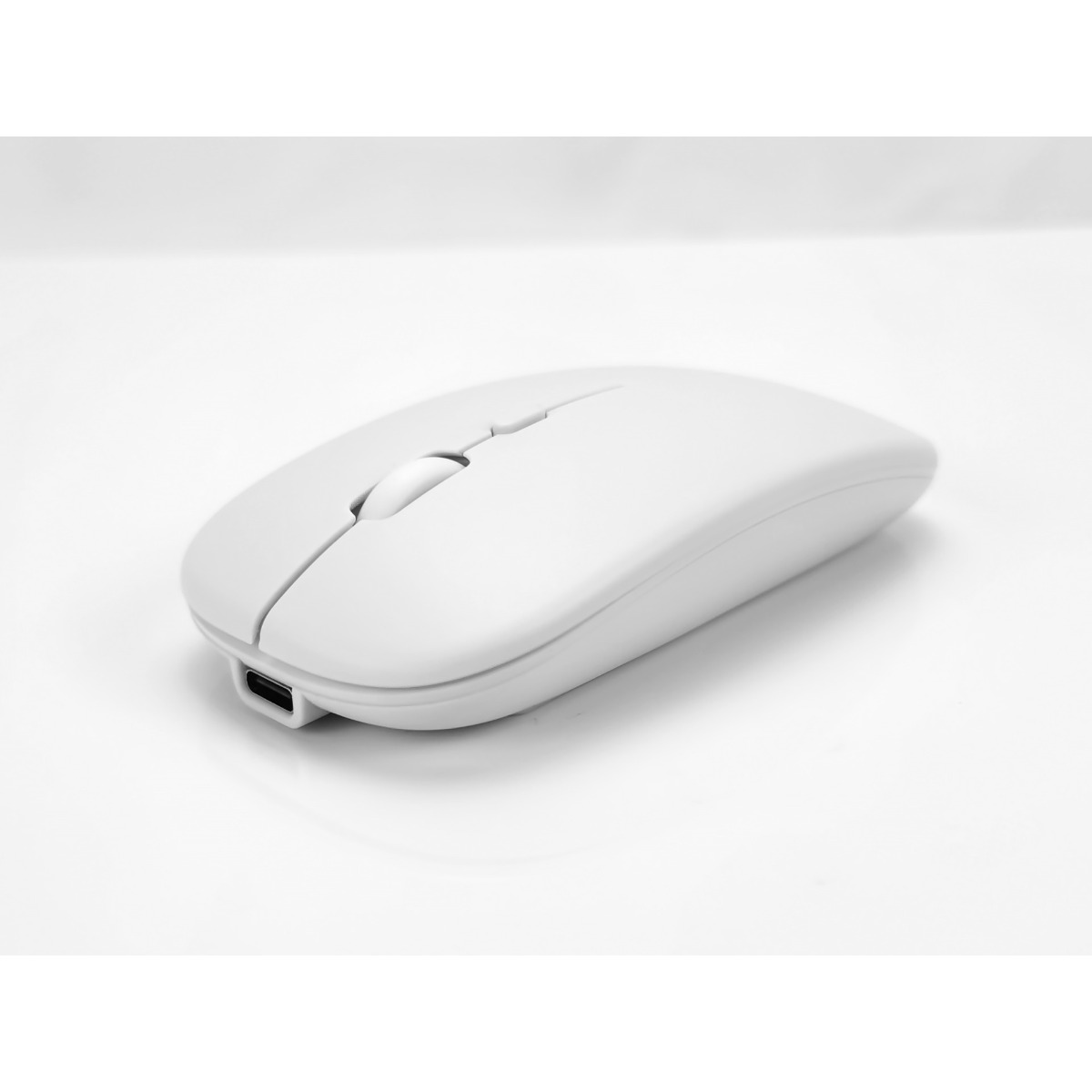 Eine weiße kabellose Computermaus mit USB-C-Anschluss auf einer hellen Oberfläche.