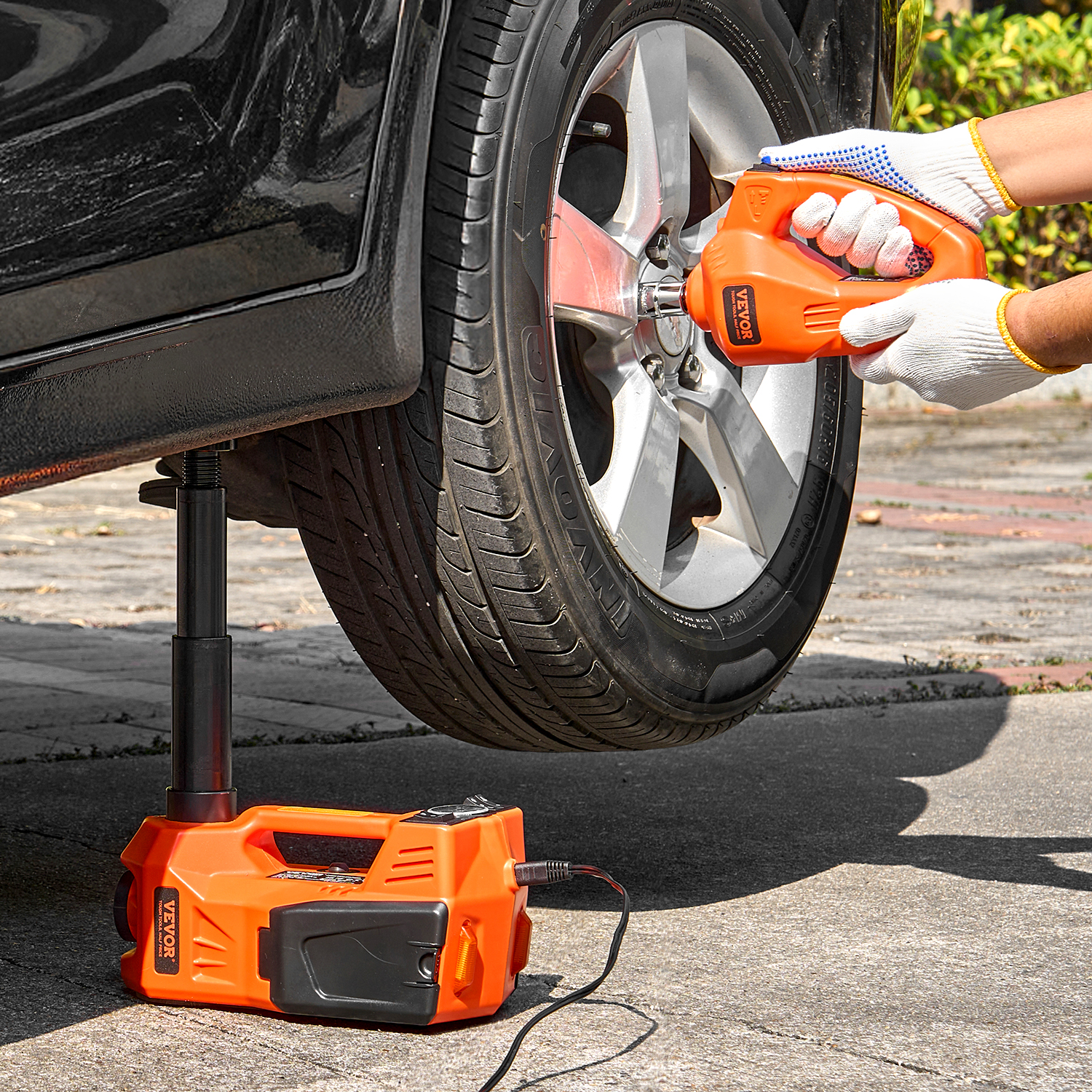 Se levanta un coche con un gato eléctrico y una llave de impacto.