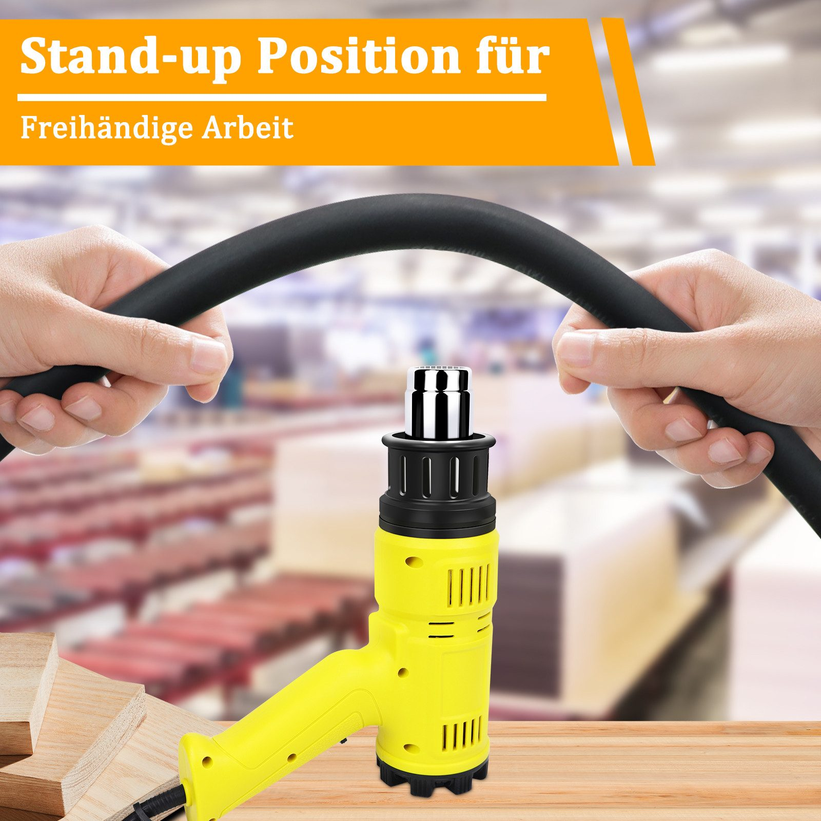 Eine gelbe Heißluftpistole steht auf einem Holztisch, Hände halten einen schwarzen Schlauch.