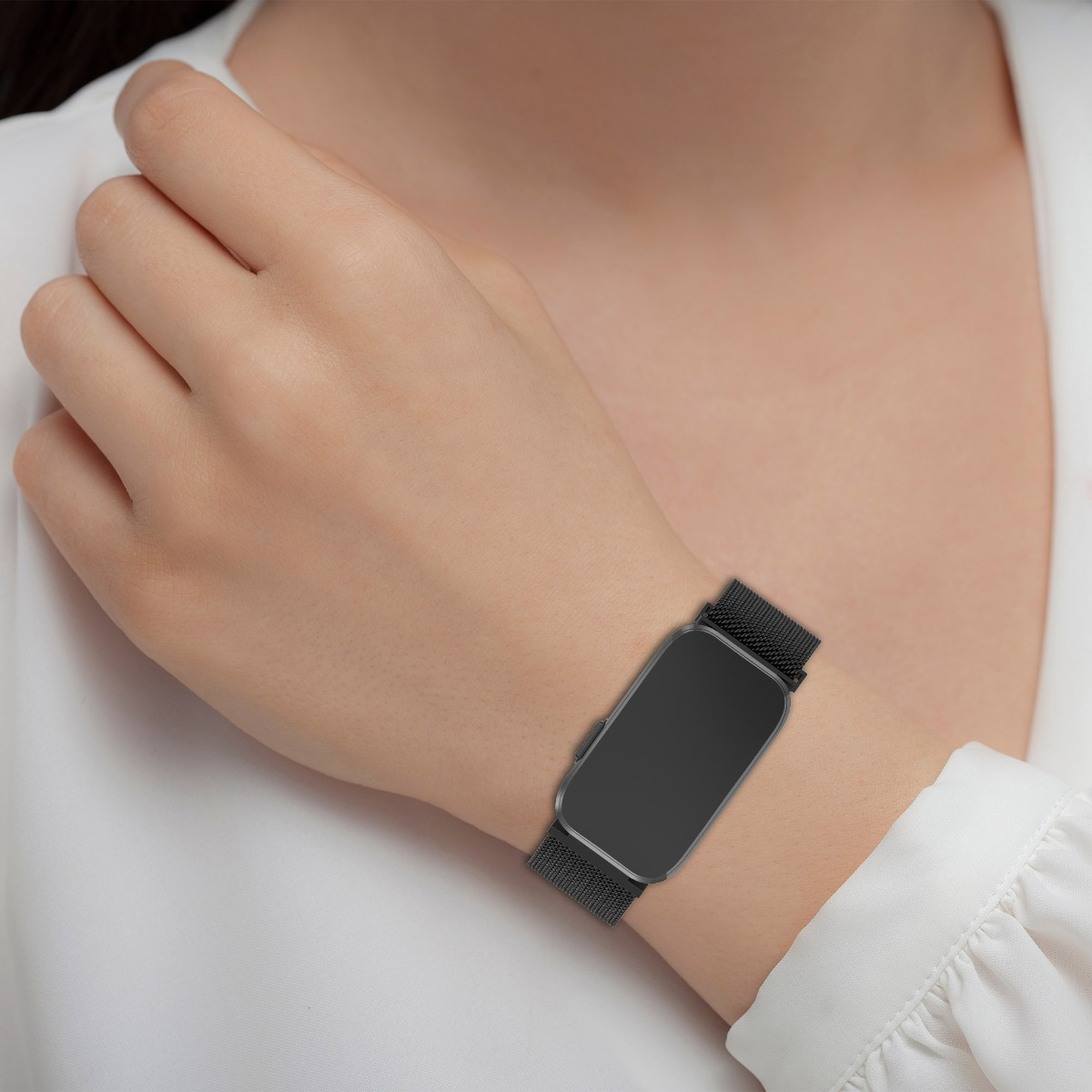 Eine Person mit weißer Bluse trägt eine elegante schwarze Smartwatch am Handgelenk.