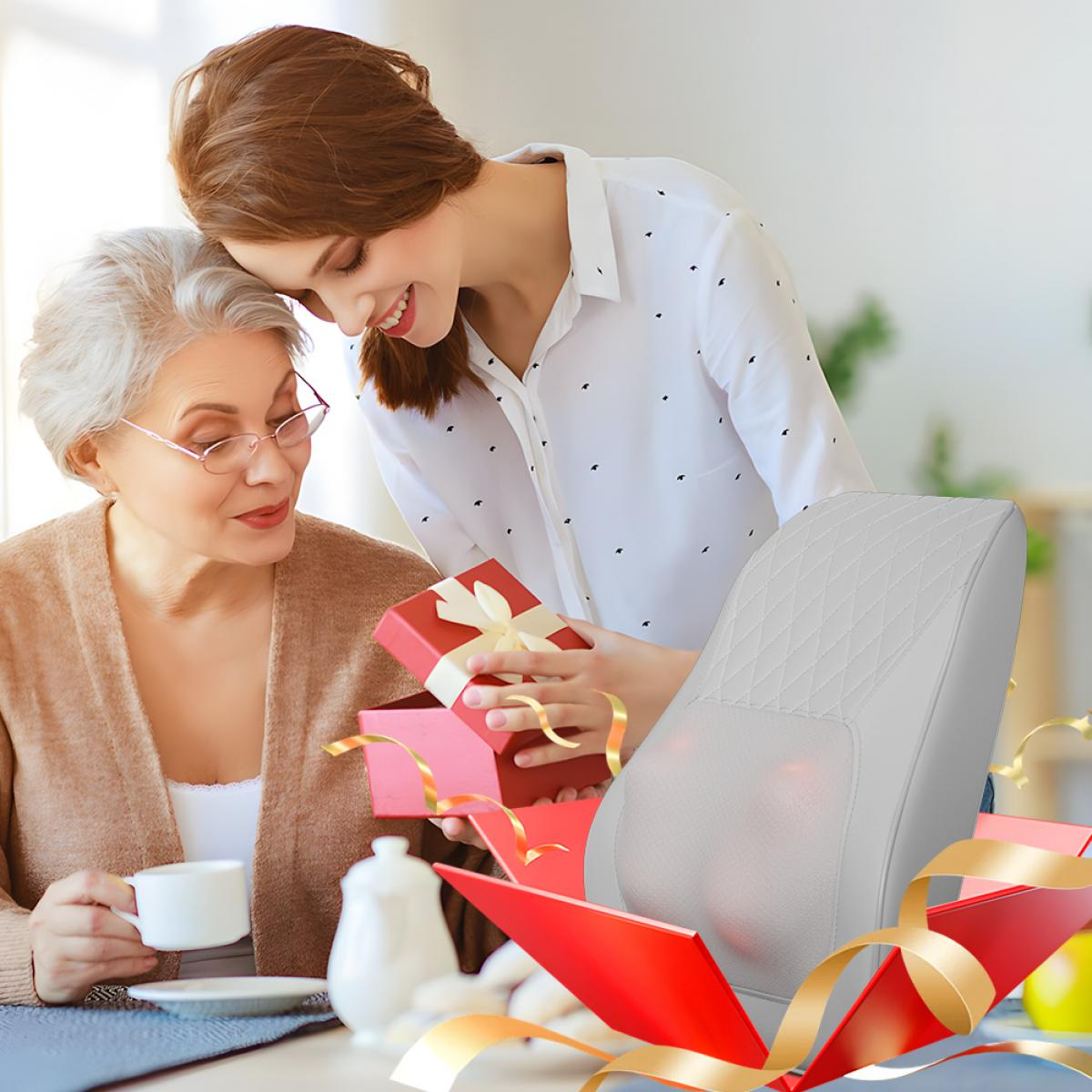 Eine junge Frau überrascht ihre ältere Mutter mit einem roten Geschenk, das ein graues Massagekissen enthält.