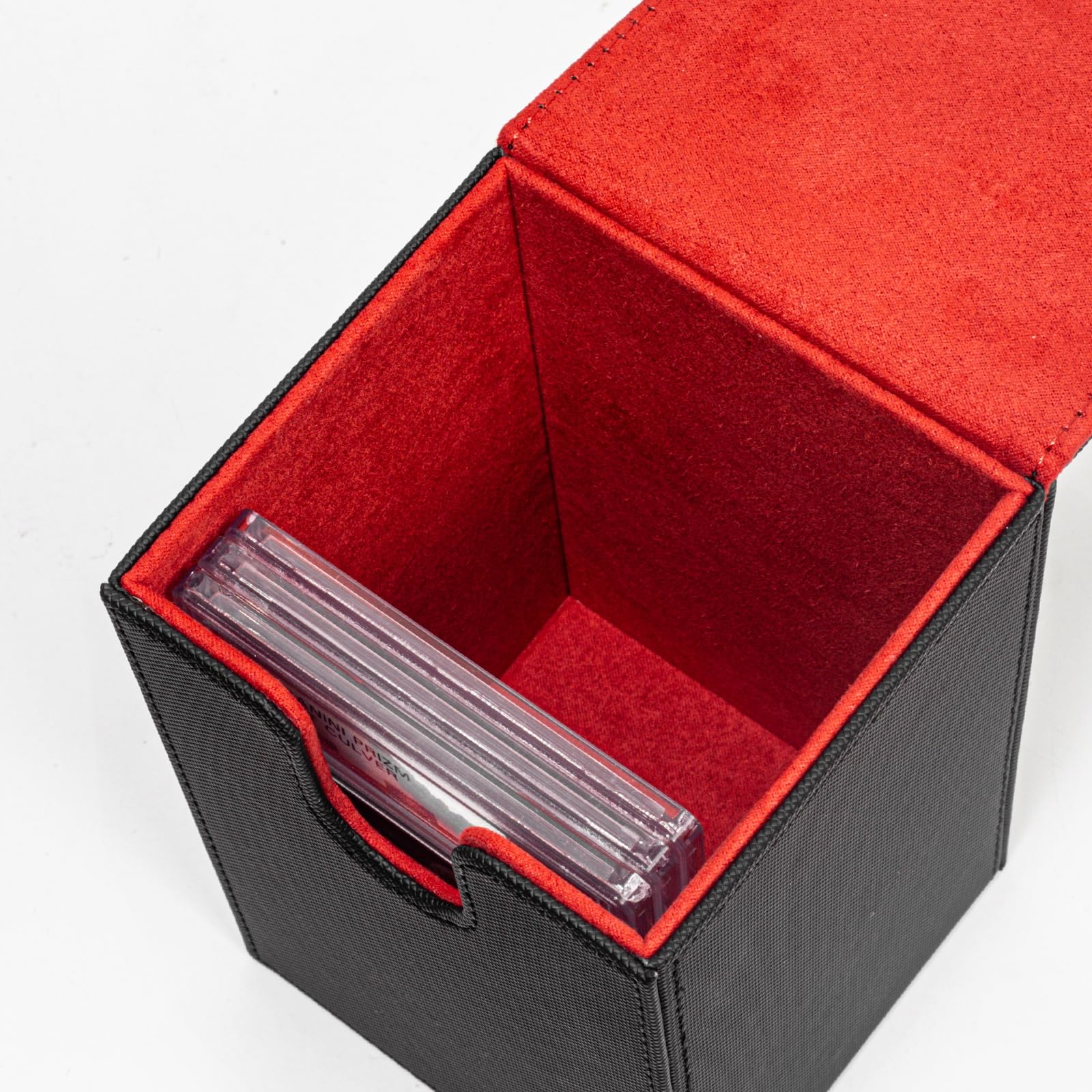 Eine offene schwarze Deckbox mit rotem Innenfutter und transparenten Sammelkarten-Hüllen.