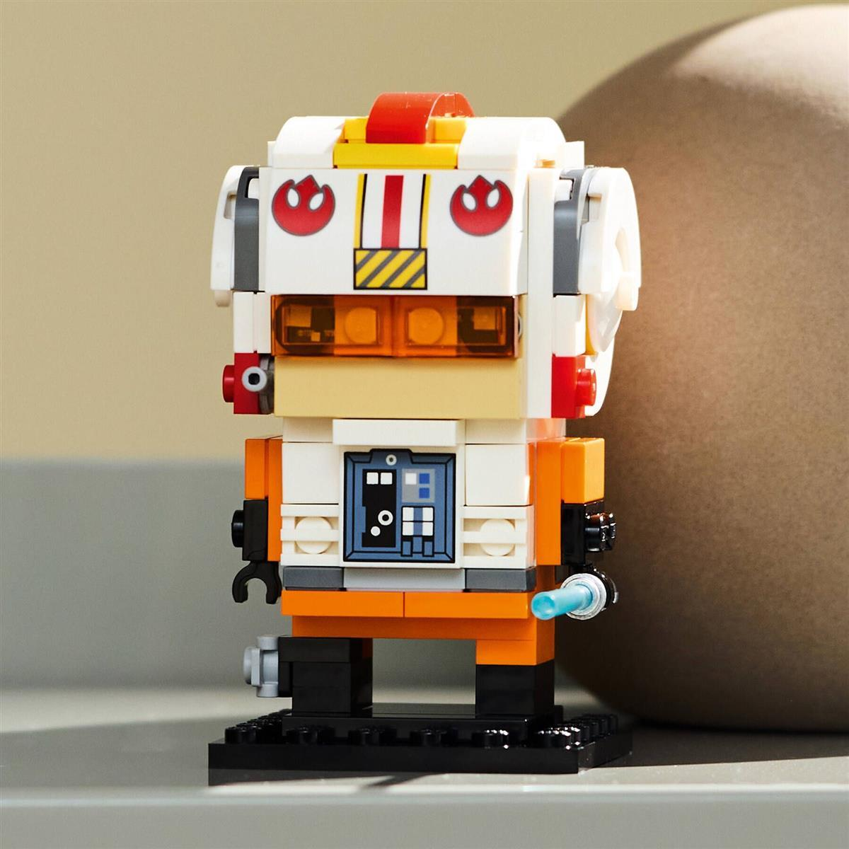 Eine Lego-Steine-Figur eines orange-weißen Piloten auf einem schwarzen Sockel.