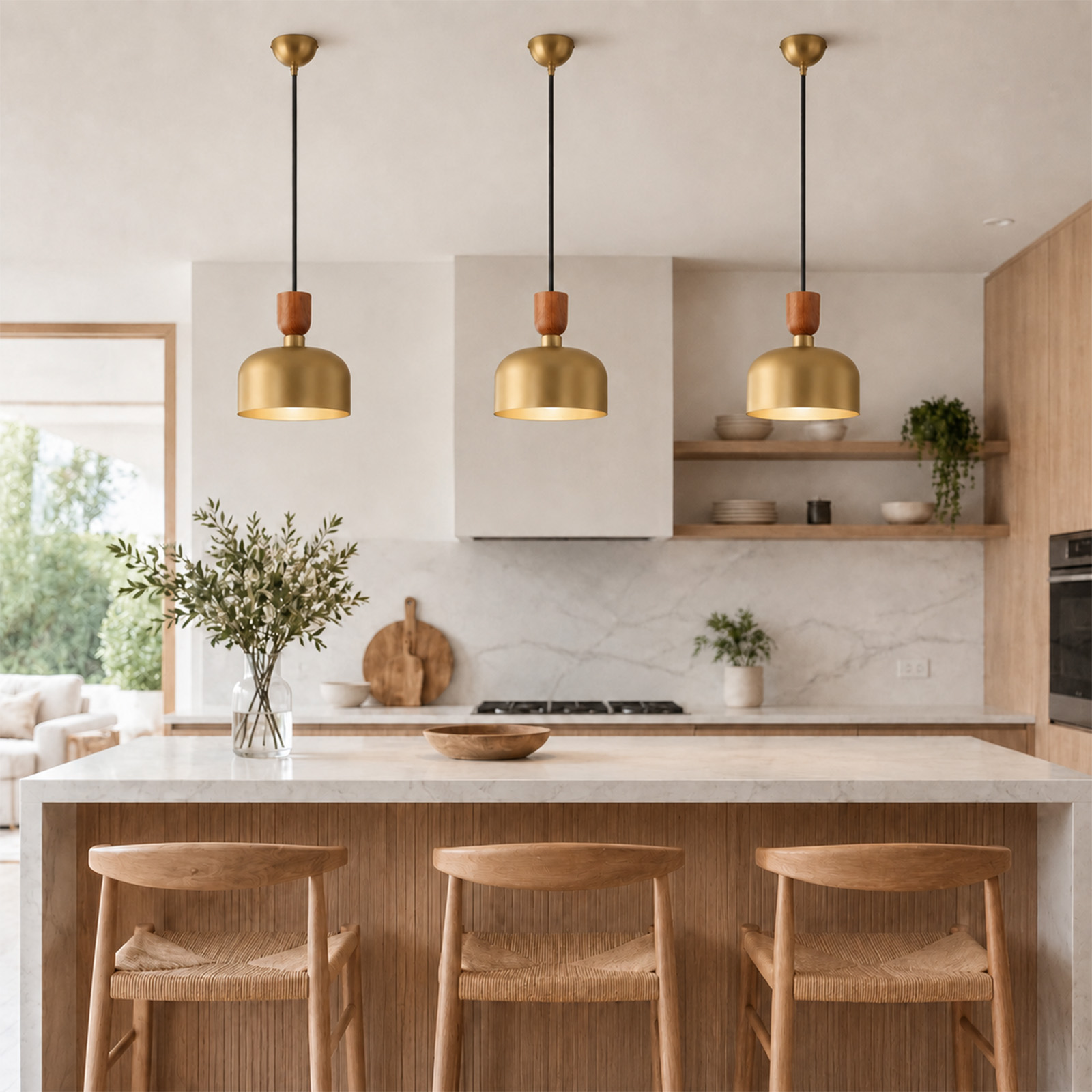 Cocina moderna con isla de mármol, tres lámparas colgantes doradas y tres taburetes de madera.