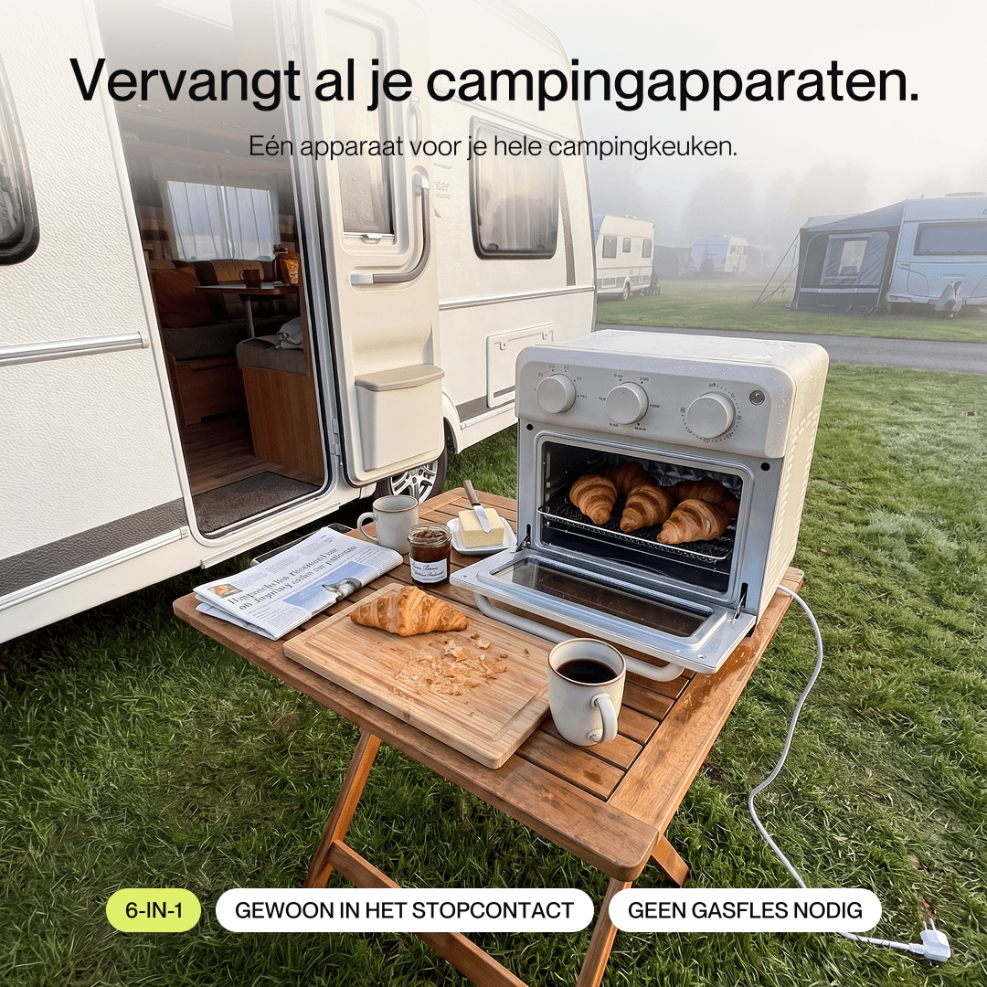 A small white oven bakes croissants on a wooden table in front of a caravan at a campsite.