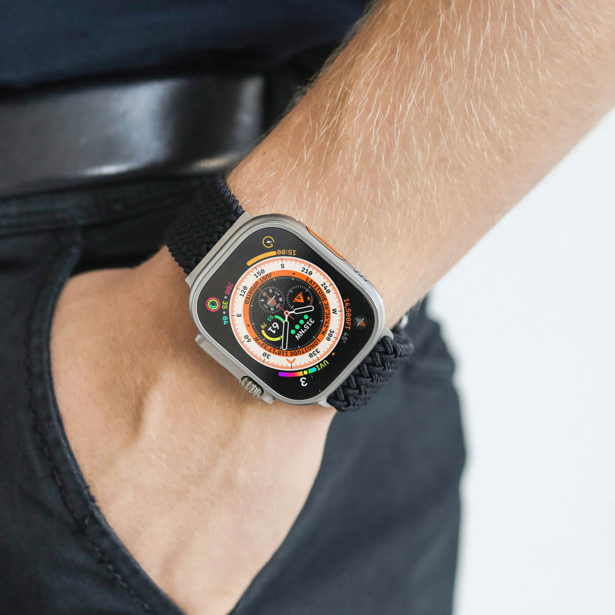Zbliżenie osoby noszącej na nadgarstku smartwatch z czarnym plecionym paskiem.