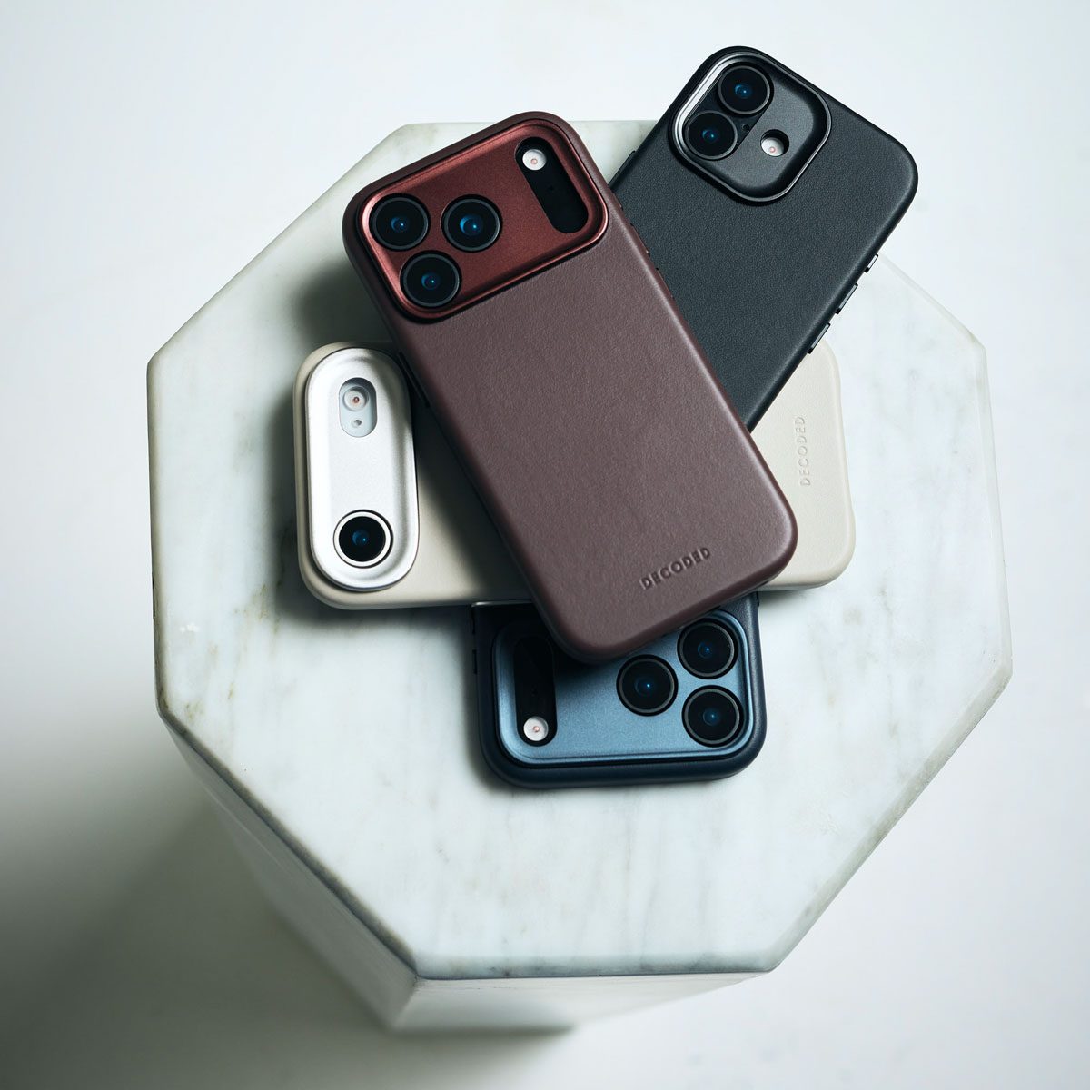 Cuatro fundas para teléfonos móviles diferentes sobre un pedestal de mármol.