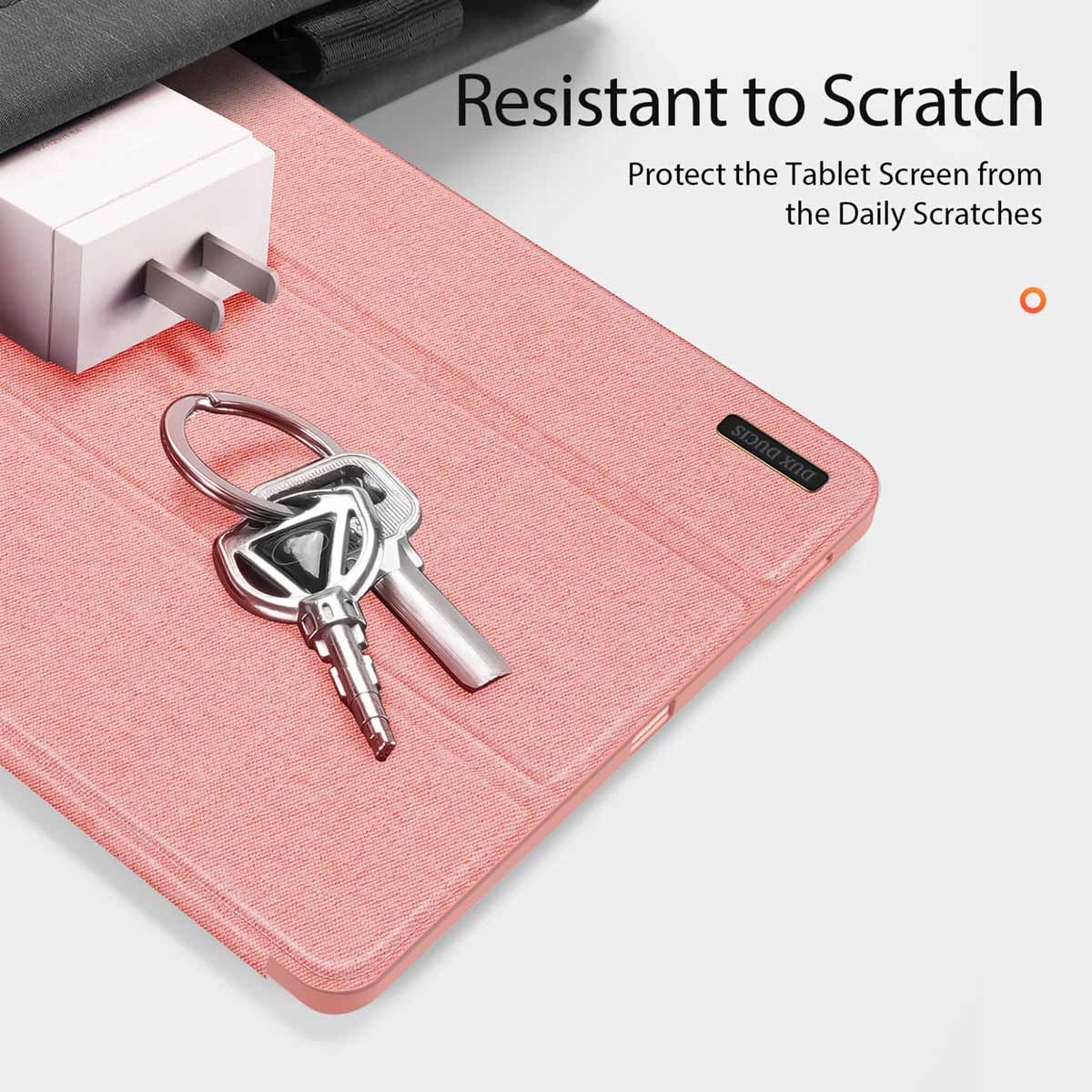Una custodia rosa per tablet con chiavi e caricabatterie sopra, con testo sulla resistenza ai graffi.