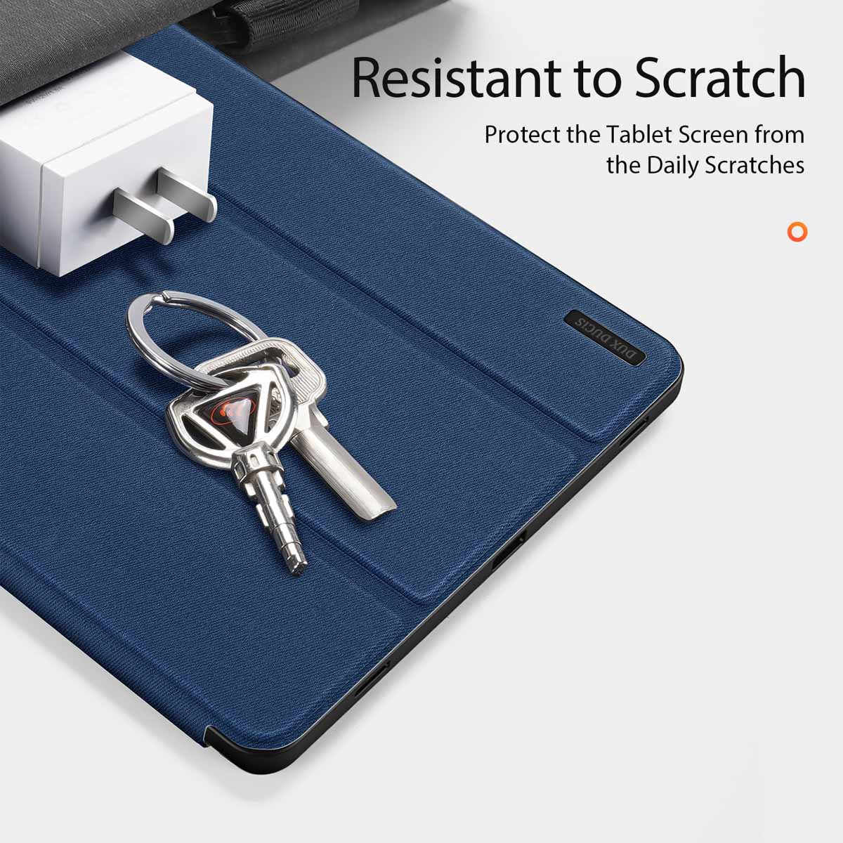 Una custodia blu per tablet con chiavi e un caricatore sopra, con il testo Resistant to Scratch.