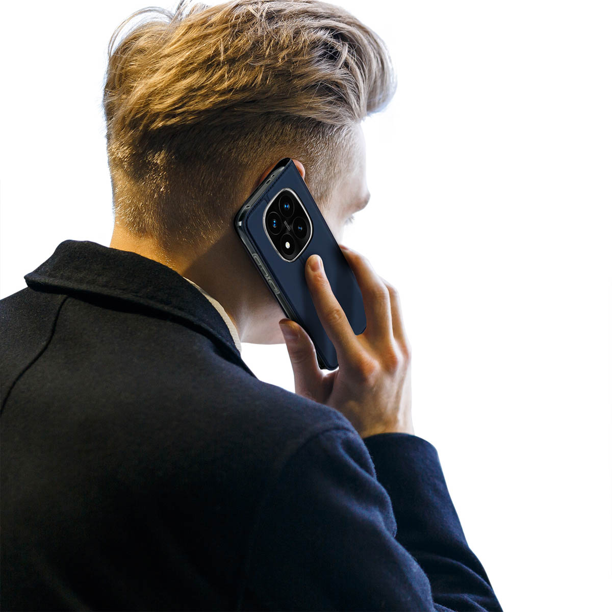 Ein blondierter Mann in dunkler Jacke telefoniert vor weißem Hintergrund mit einem Smartphone.