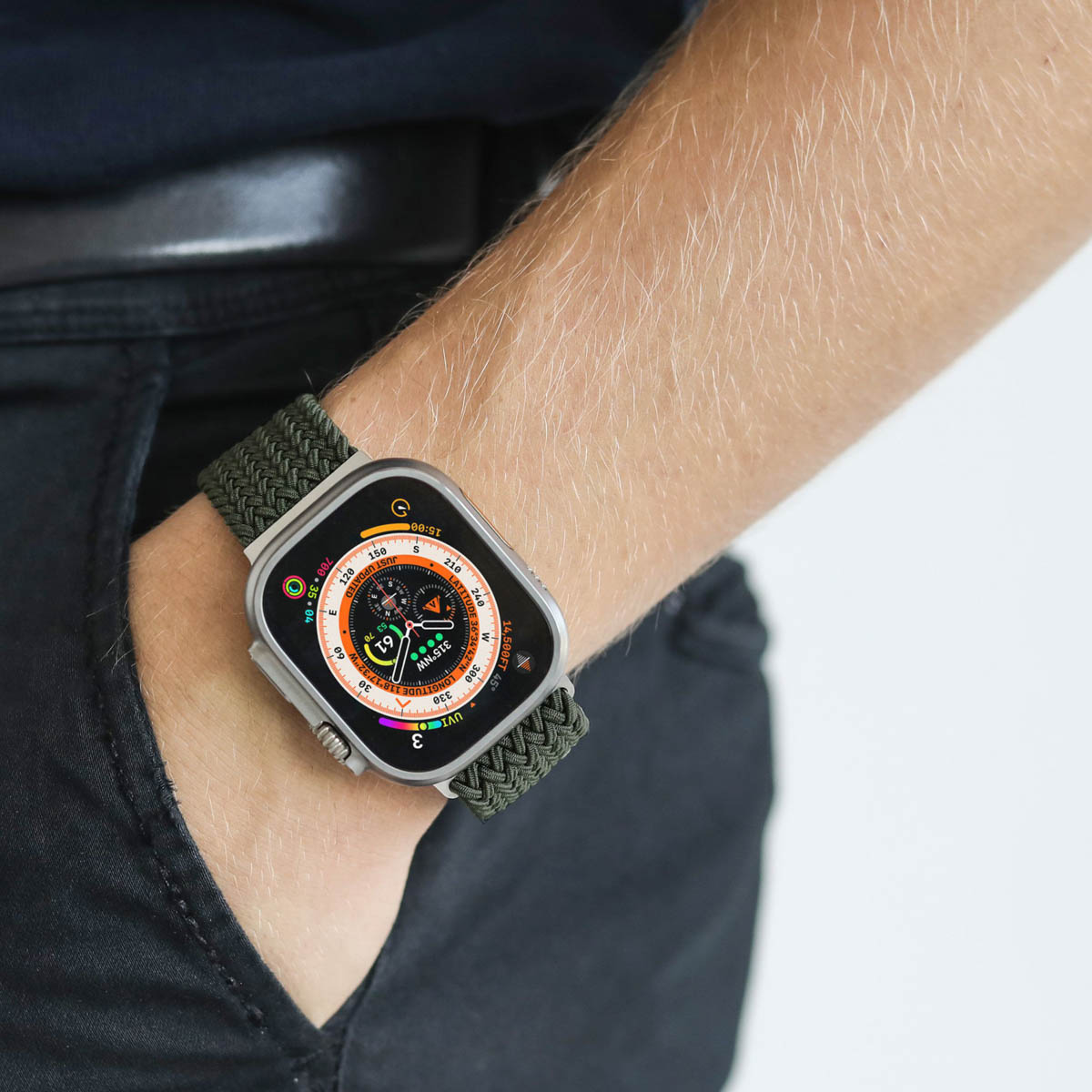 Eine Apple Watch Ultra mit grünem Stoffarmband am Arm einer Person.