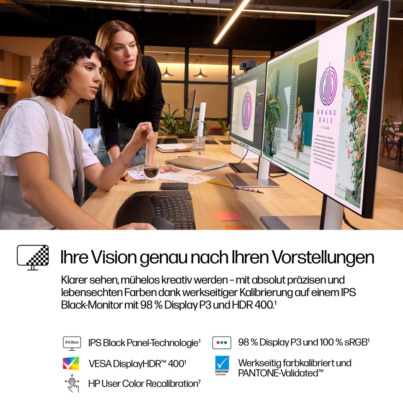 Due donne lavorano a una moderna scrivania in legno davanti a grandi monitor.