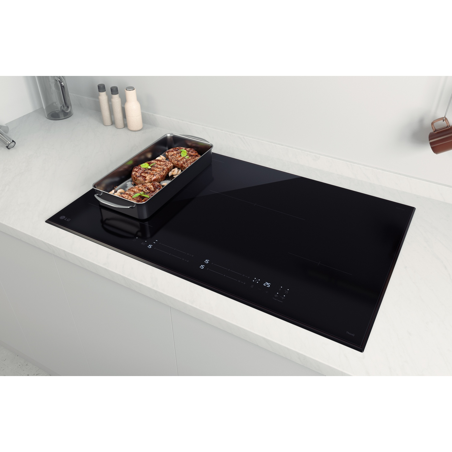 Piano cottura a induzione nero su piano bianco con padella contenente bistecche e aglio.