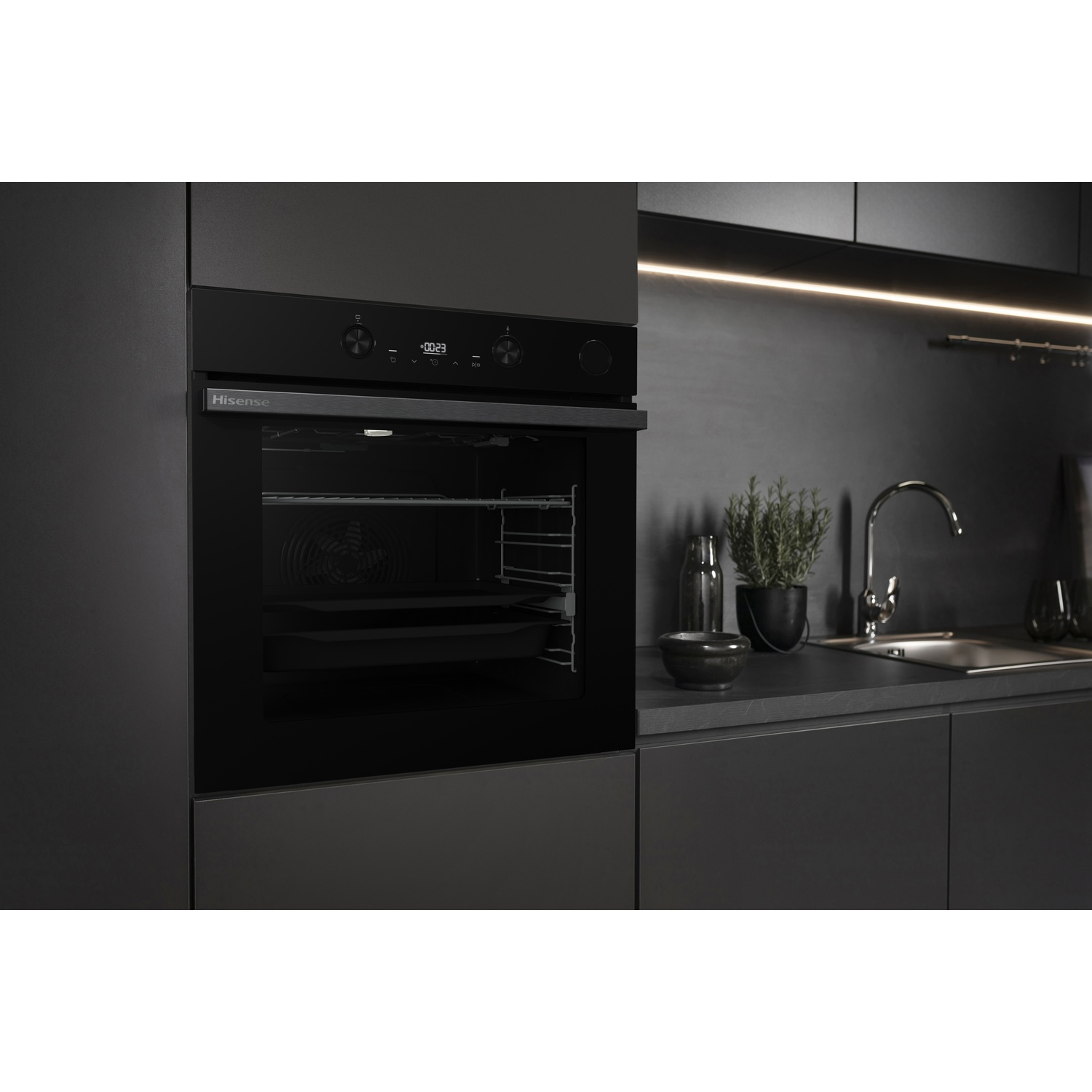 Moderno forno da incasso Hisense nero in una cucina scura ed elegante con lavello e pianta sullo sfondo.