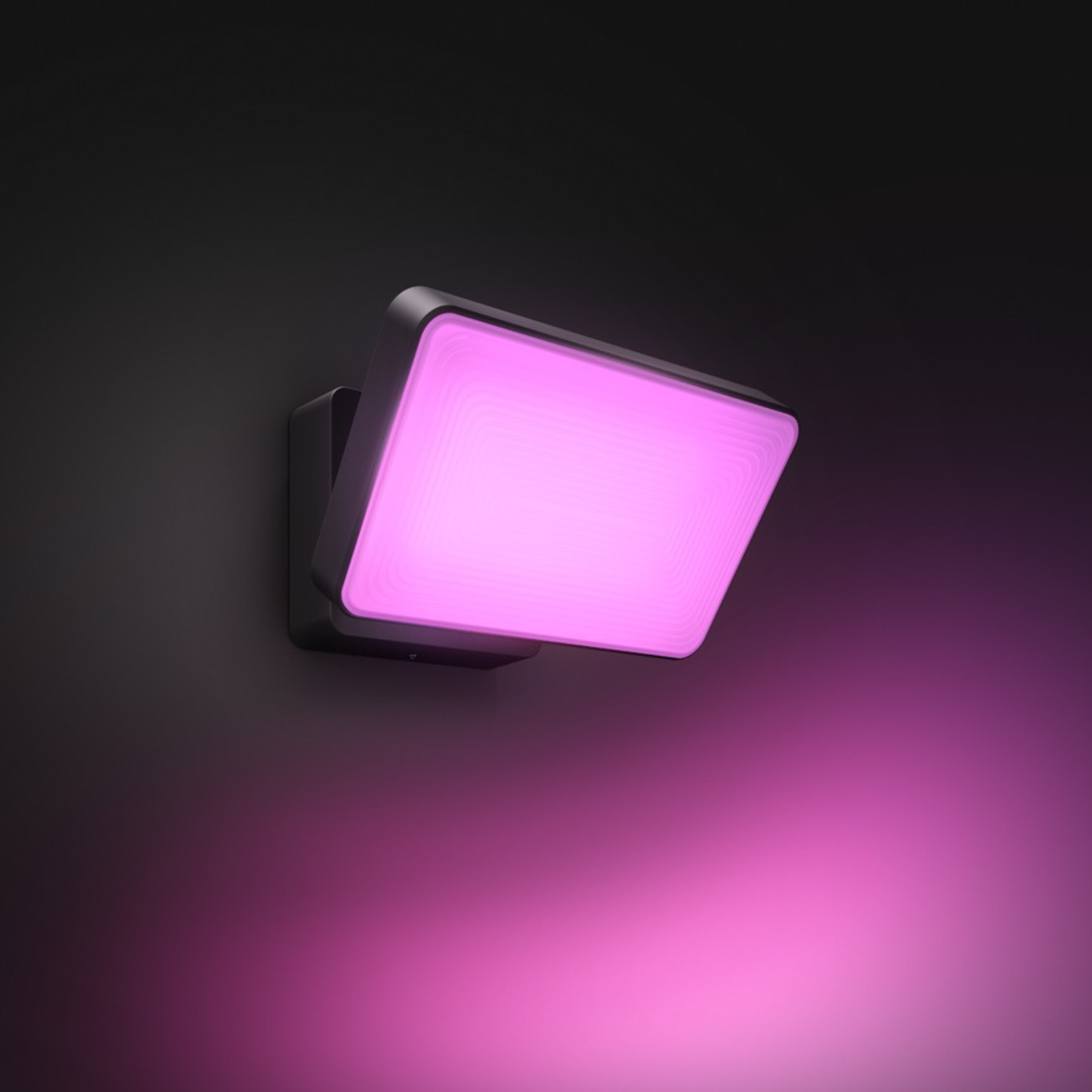 Eine schwarze Wandlampe strahlt ein leuchtendes rosa Licht an eine dunkle Wand.