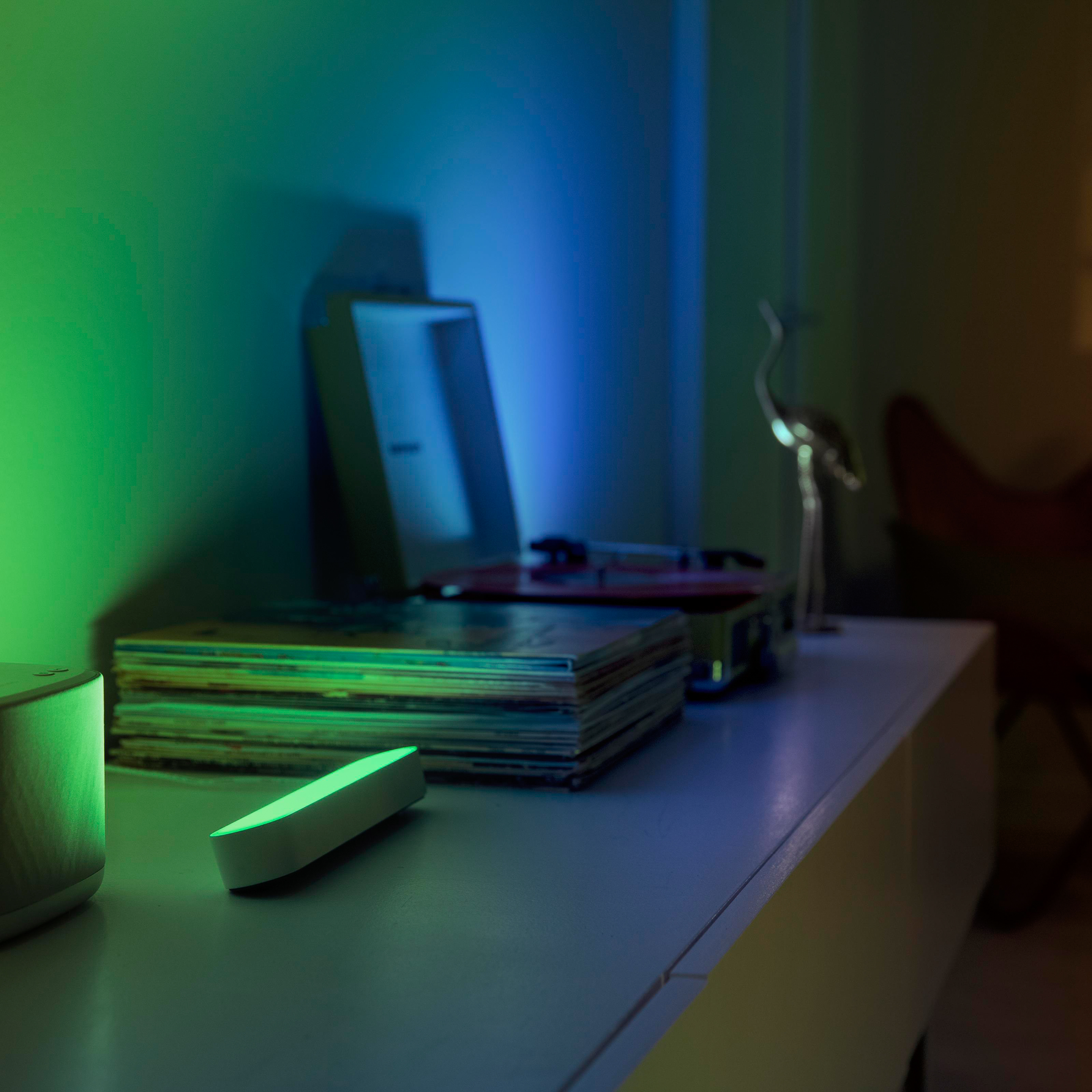 Eine weiße Kommode mit Schallplatten, einem Plattenspieler und grün-blauem Licht.