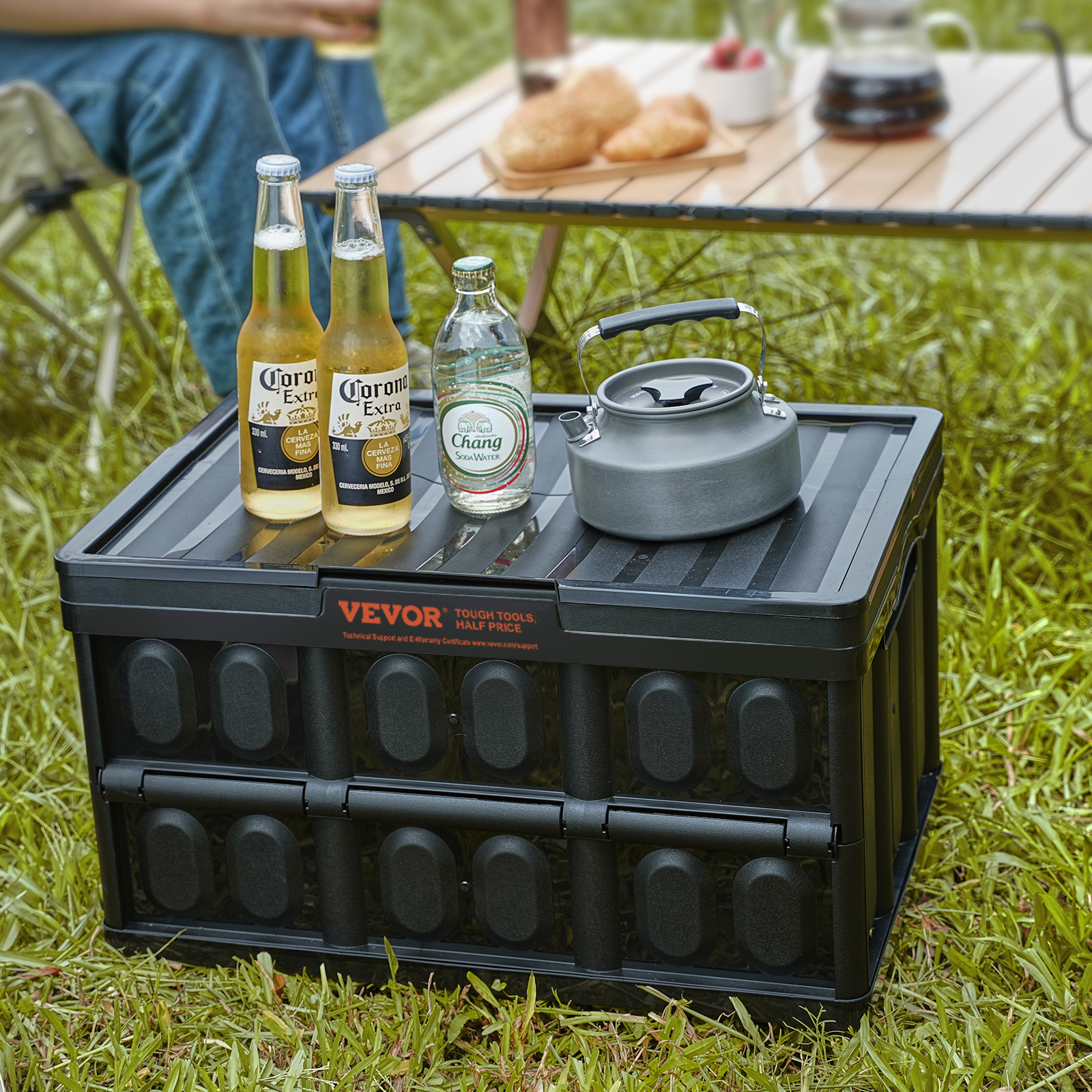 Auf einer schwarzen Box im Gras stehen zwei Corona-Flaschen, eine Chang-Flasche und ein grauer Kessel.