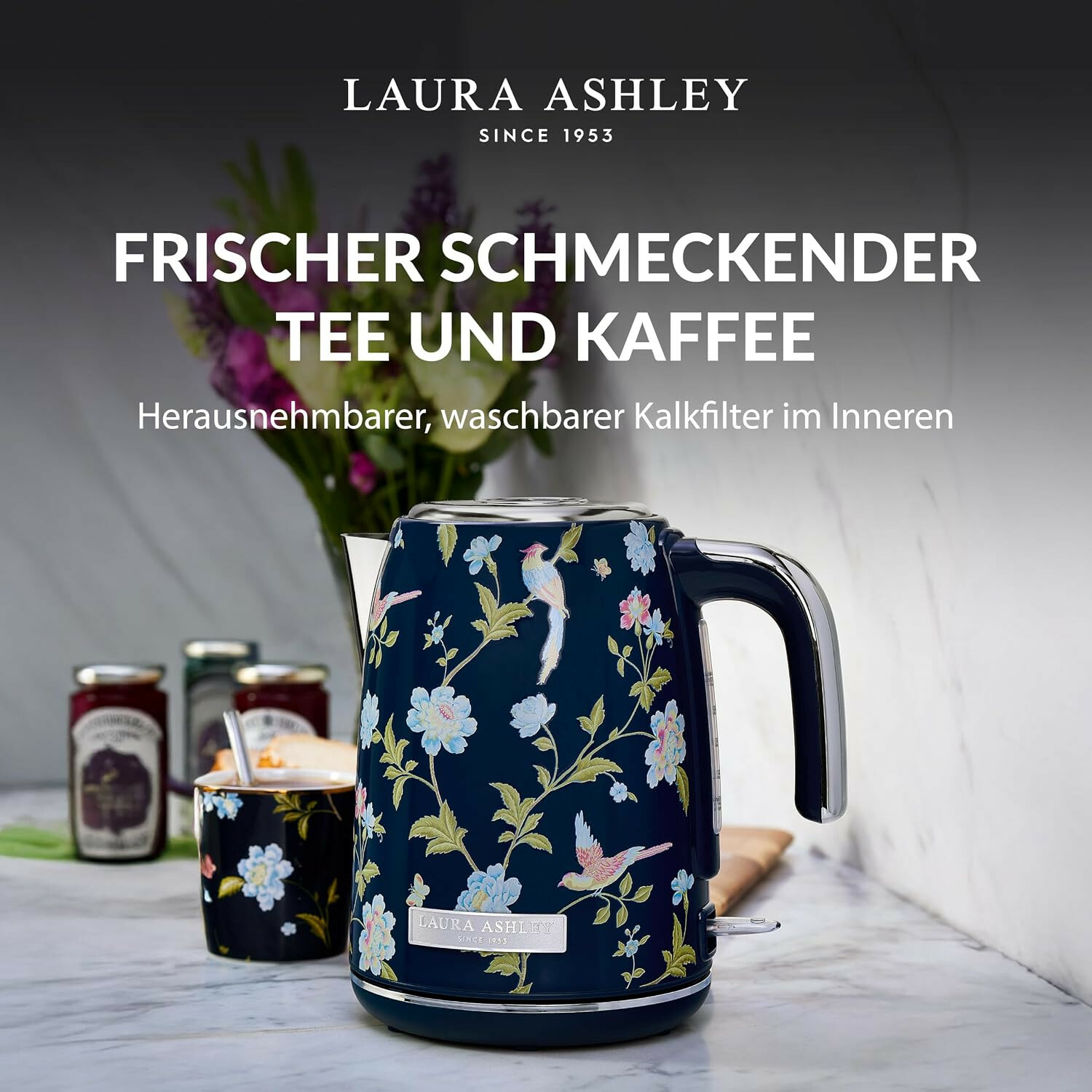 Ein blauer Laura Ashley Wasserkocher mit Blumen- und Vogelmuster steht auf einer Marmorarbeitsplatte.