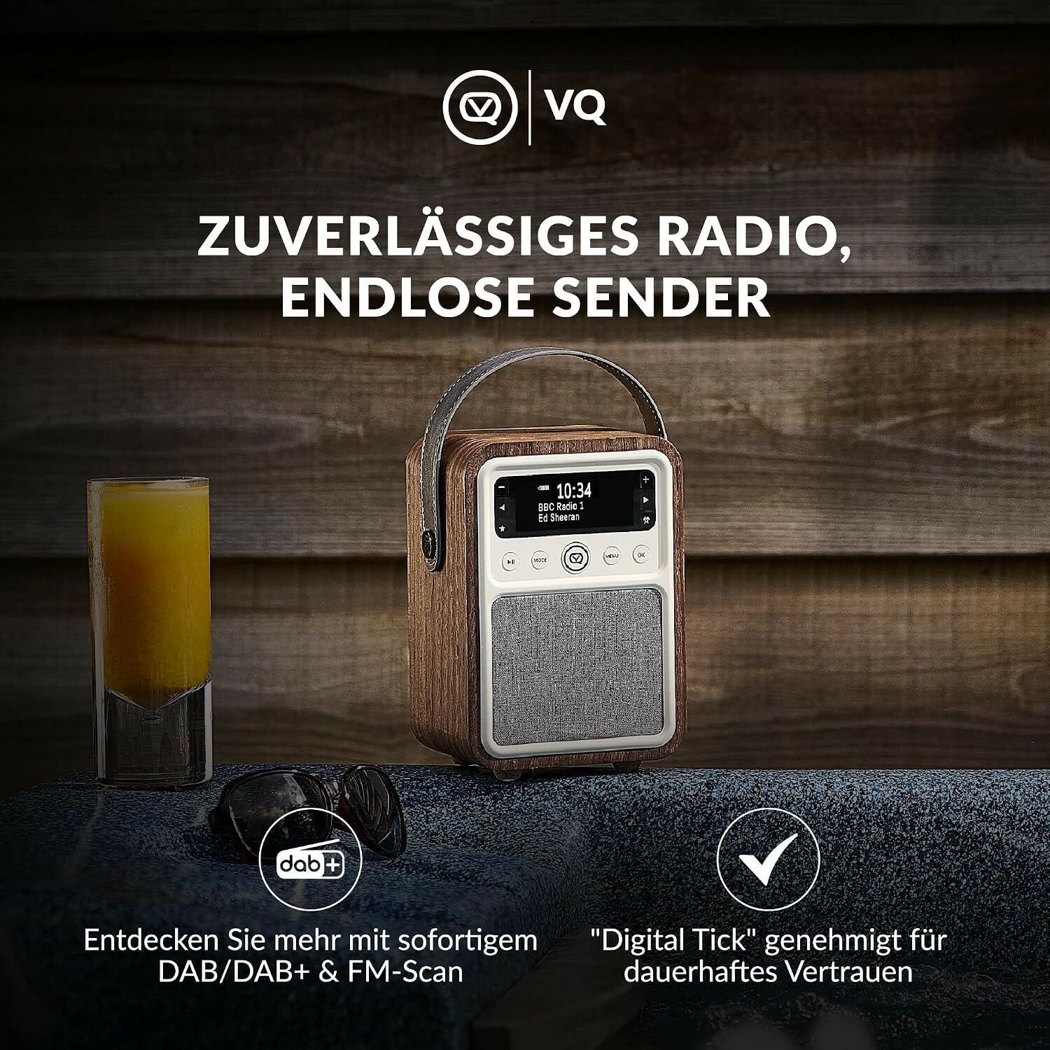 Holzradio mit Ledergriff vor Holztafel, links Glas Orangensaft und Brille, unten DAB+ und Haken-Icons, deutscher Text.