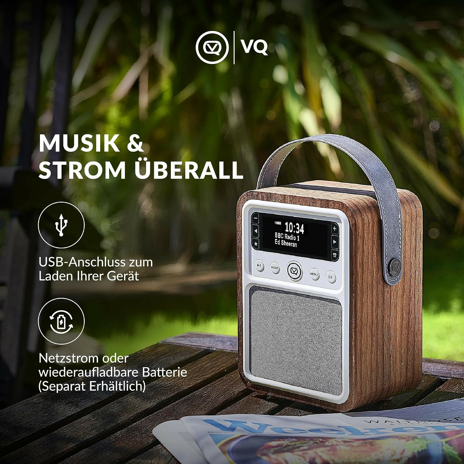 Ein hölzernes tragbares Radio mit grauem Tragegriff und Display steht auf einem Tisch draußen.