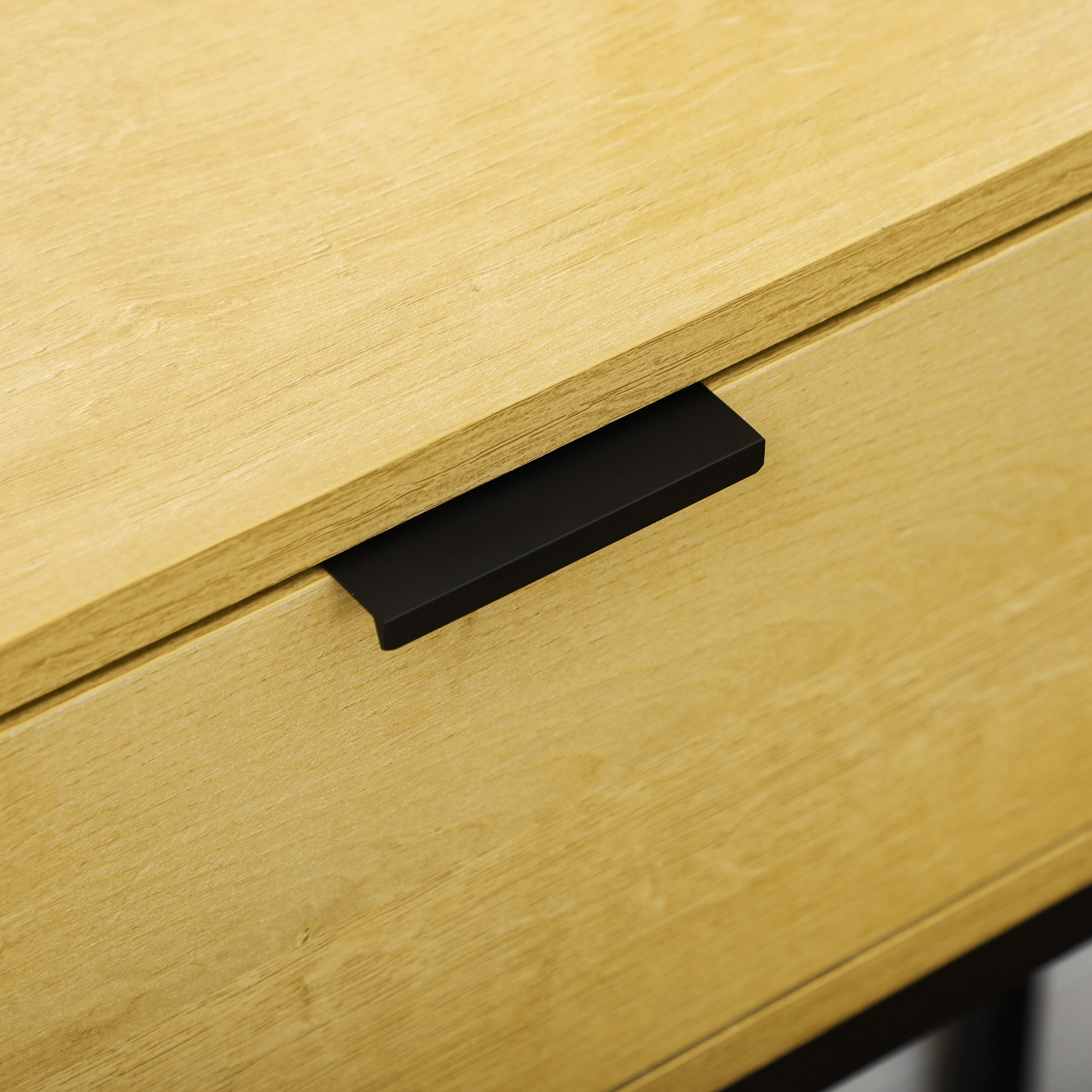 Primer plano de una cómoda de madera clara con tirador negro mate.