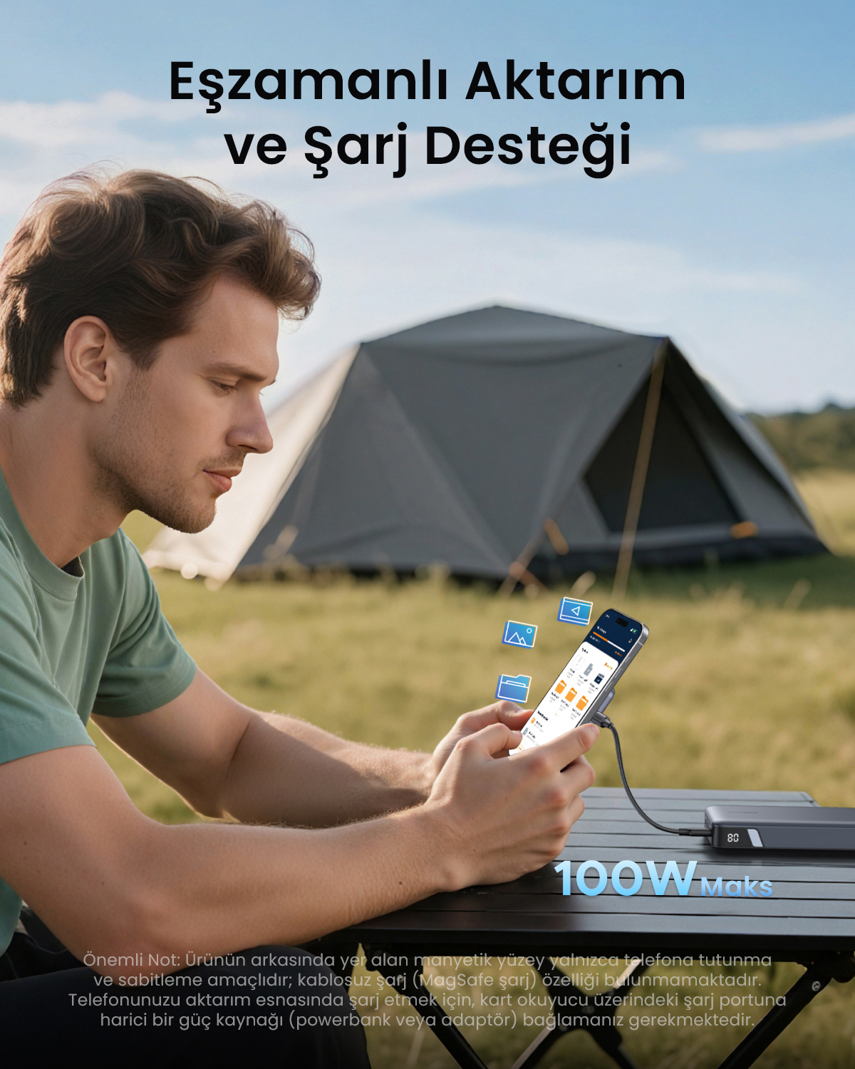 Un uomo siede a un tavolo all'aperto con una tenda sullo sfondo e usa lo smartphone.