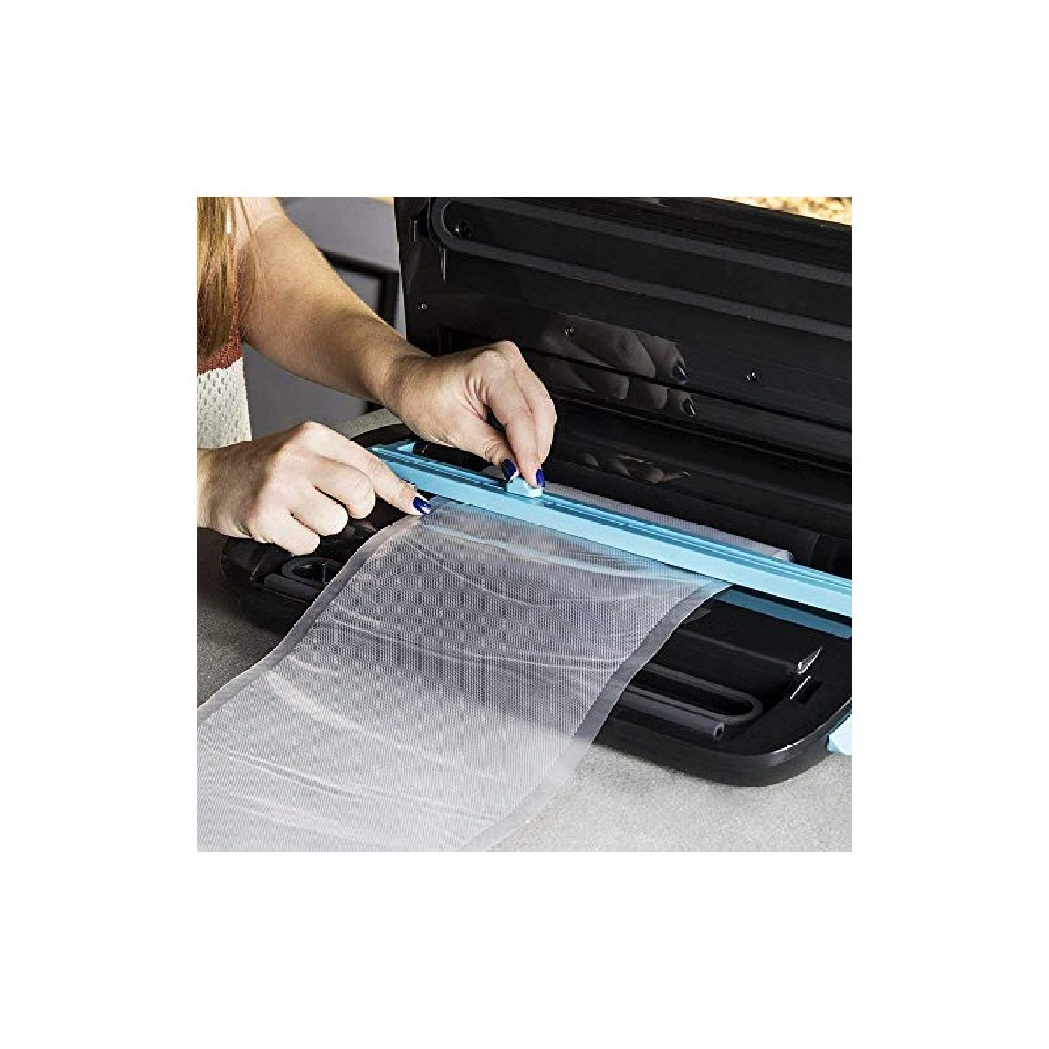 Una persona usa una macchina sottovuoto per sigillare un rotolo di plastica.