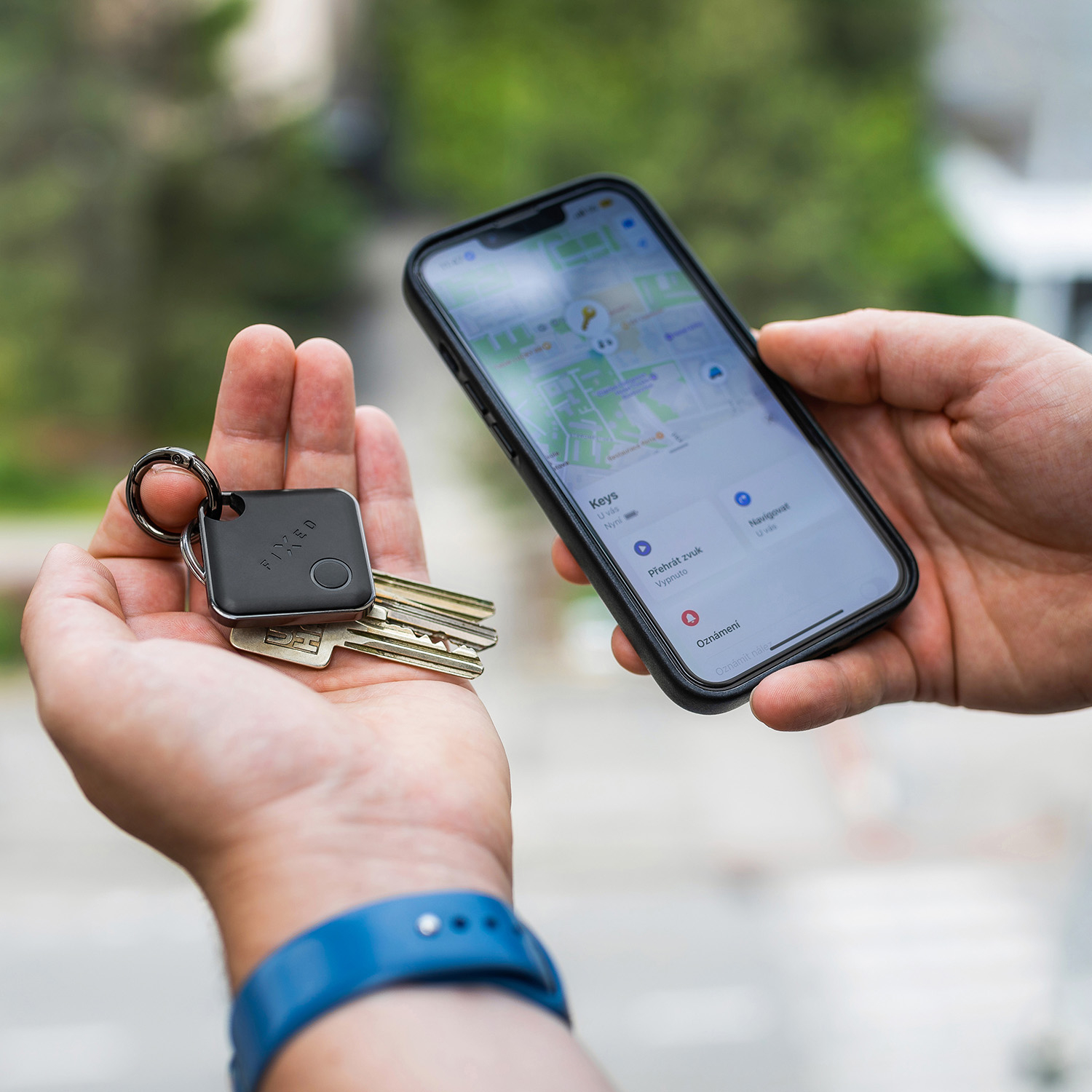 Person hält Schlüssel mit intelligentem Finder und ein Smartphone mit Tracking-App in den Händen.