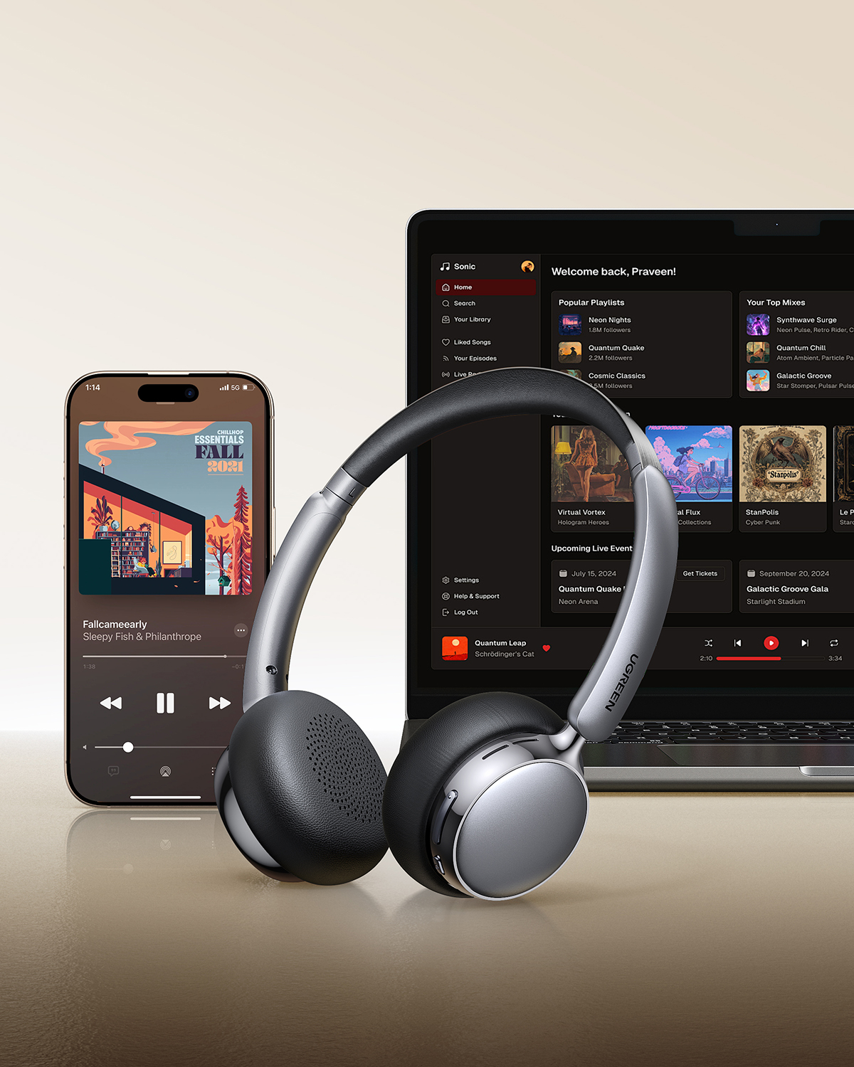 Cuffie wireless grigie davanti a uno smartphone e un laptop con app musicali.