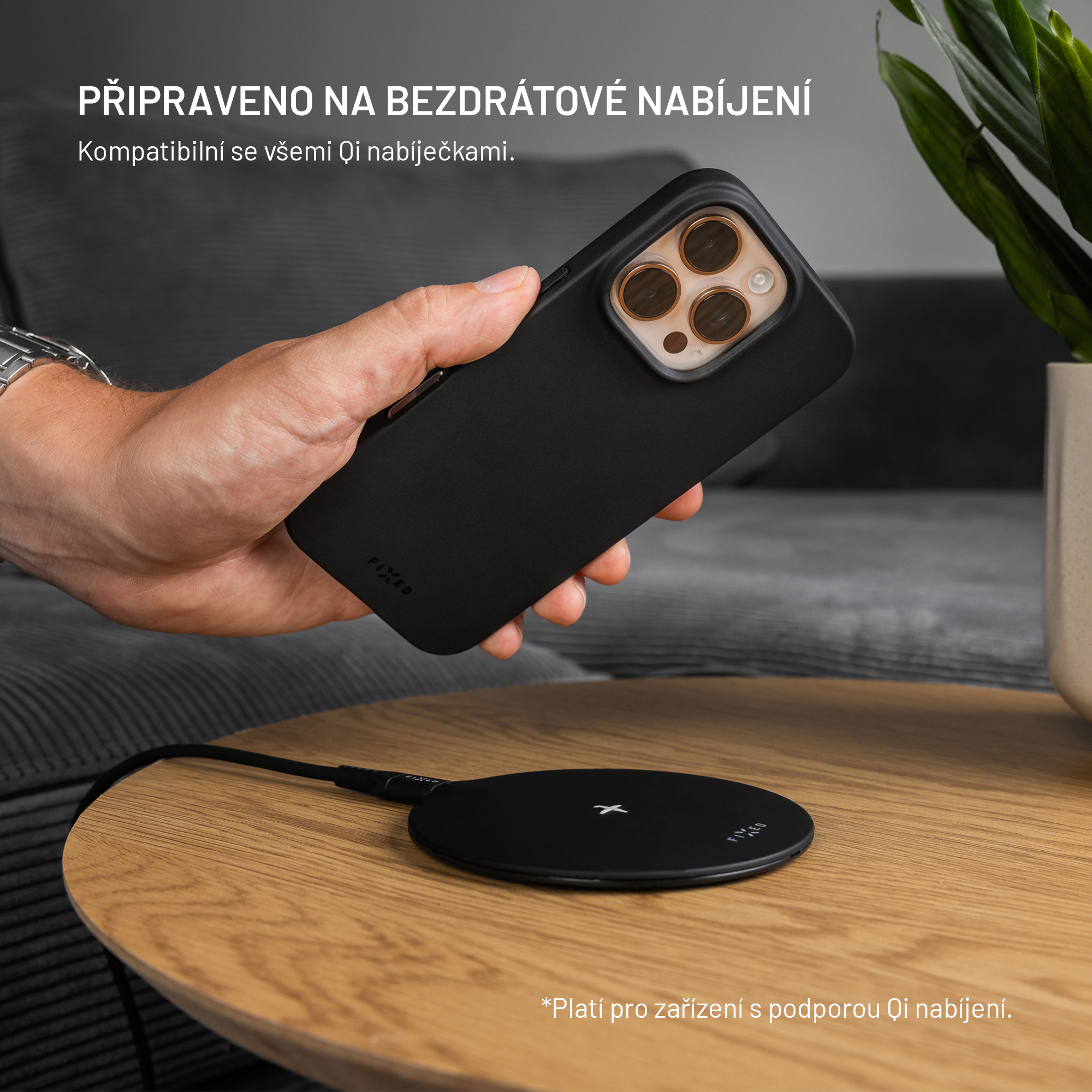 Eine Hand hält eine schwarze Handyhülle über ein kabelloses Ladegerät.