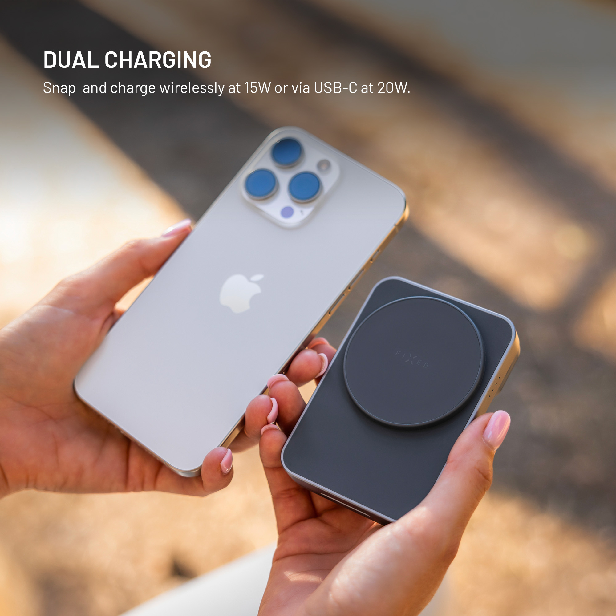 Mani che tengono uno smartphone e un power bank magnetico grigio scuro con la scritta DUAL CHARGING.
