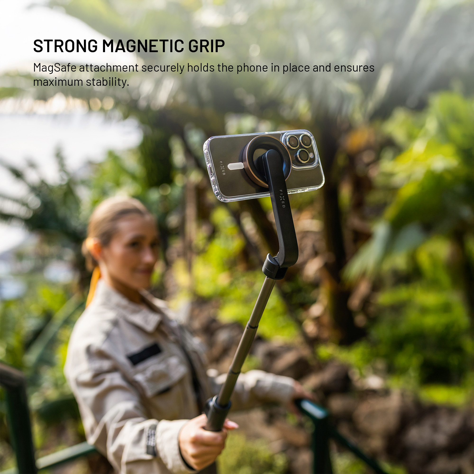 Eine Frau hält im Freien einen Selfie-Stick mit einem magnetisch befestigten Smartphone.