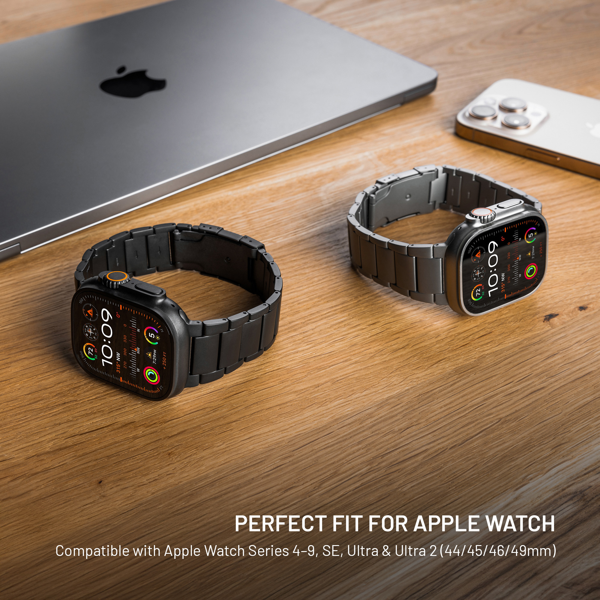 Zwei Apple Watches mit Metallarmbändern auf einem Holztisch mit Laptop und Telefon.
