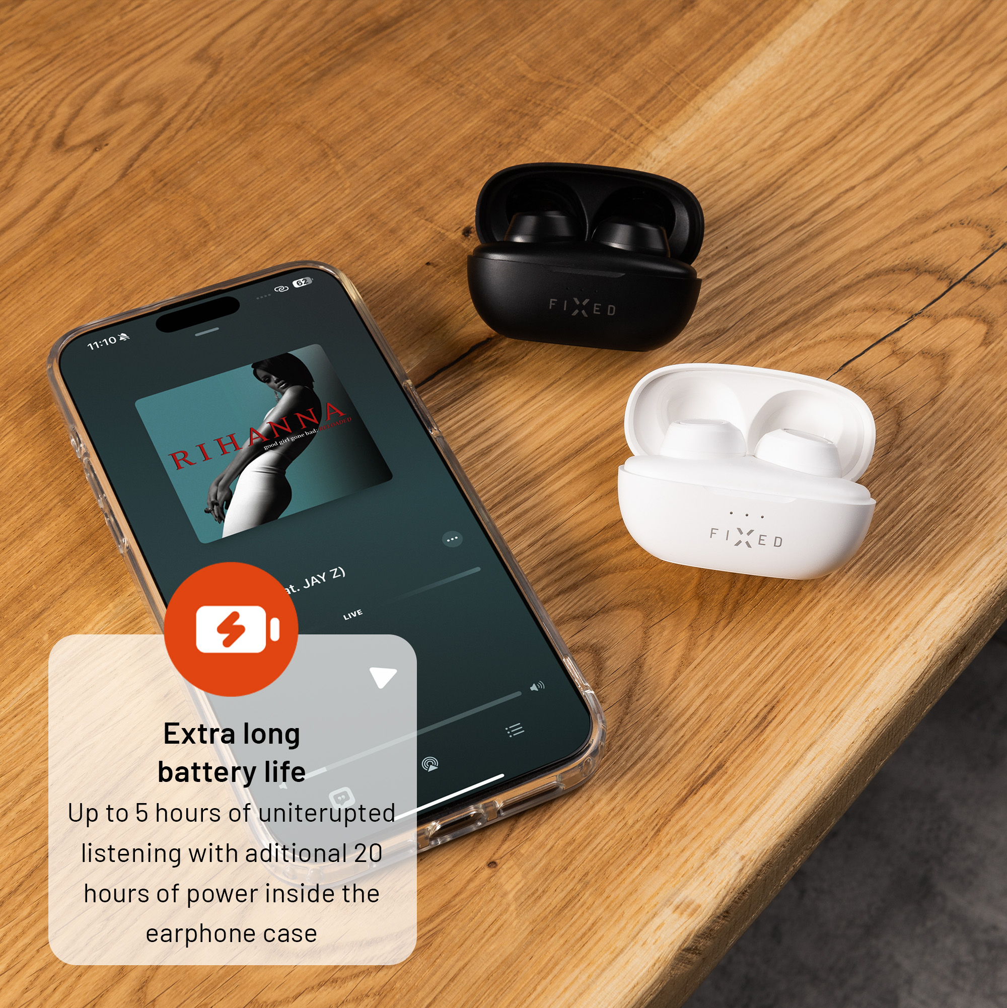 Smartphone mit Musik-App und weiße sowie schwarze Kopfhörer auf Holztisch.