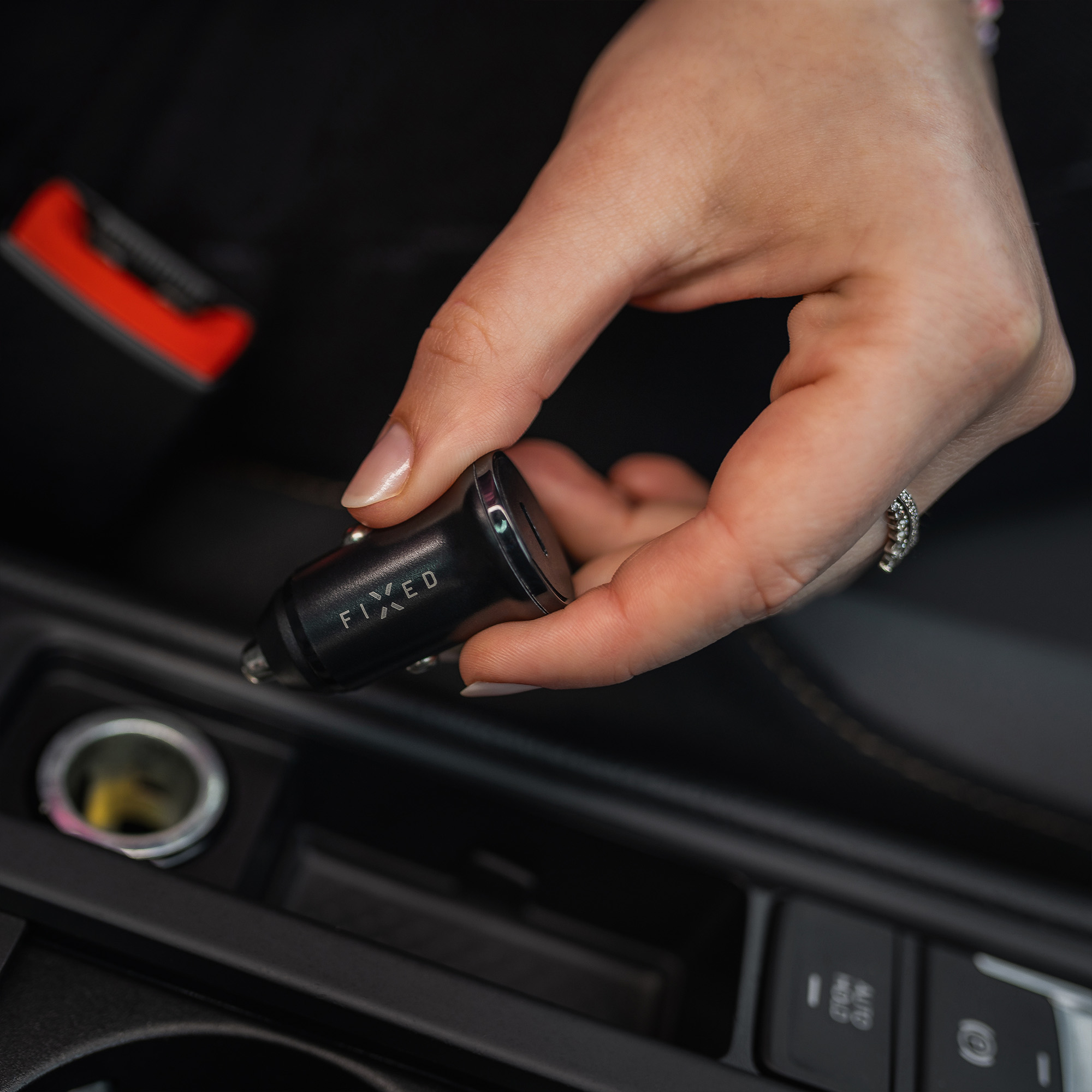 Eine Hand hält ein schwarzes Fixed Autoladegerät in der Nähe einer Steckdose.