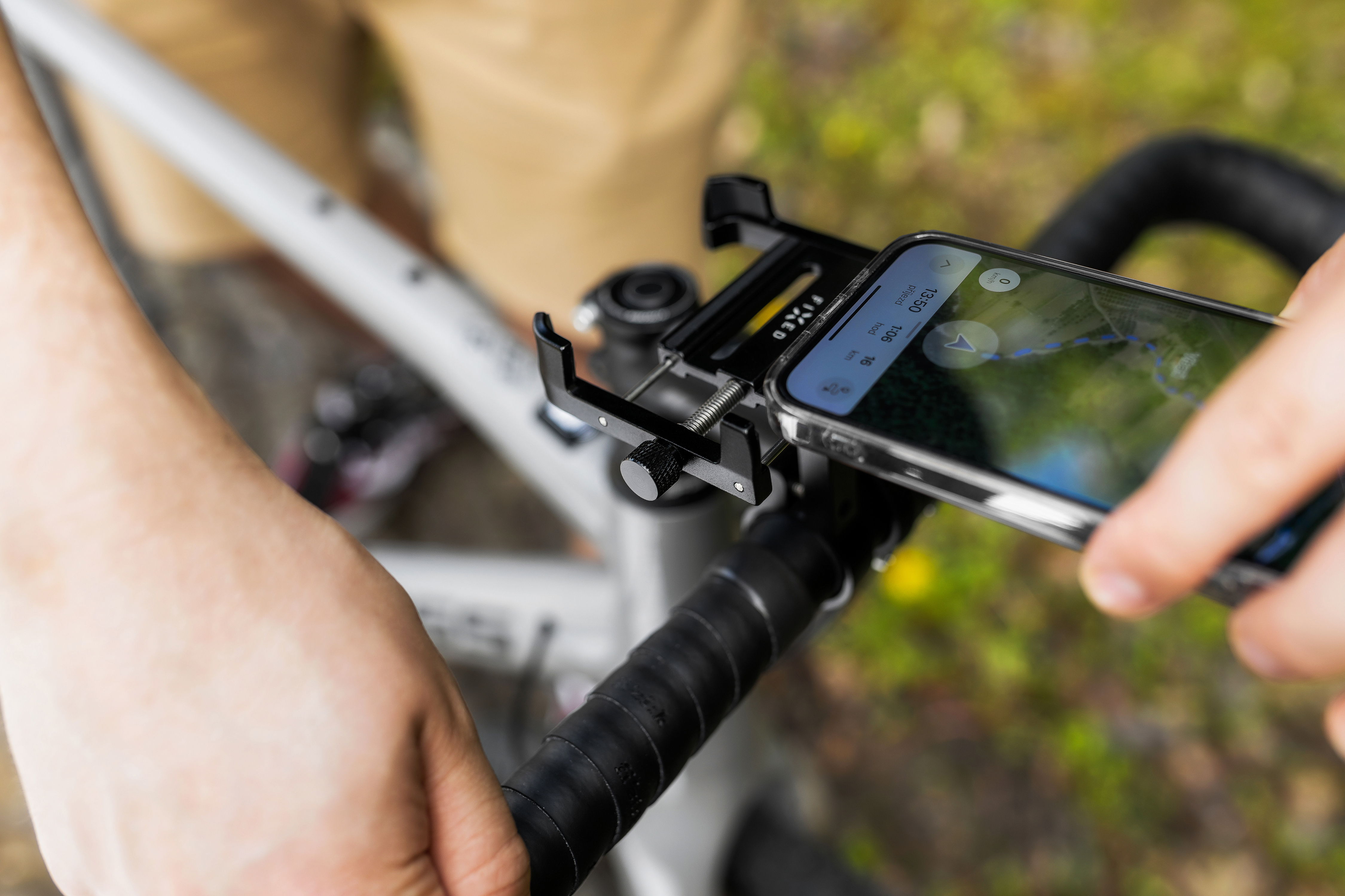 Eine Person befestigt ein Smartphone an einer schwarzen Lenkerhalterung an einem Fahrrad.