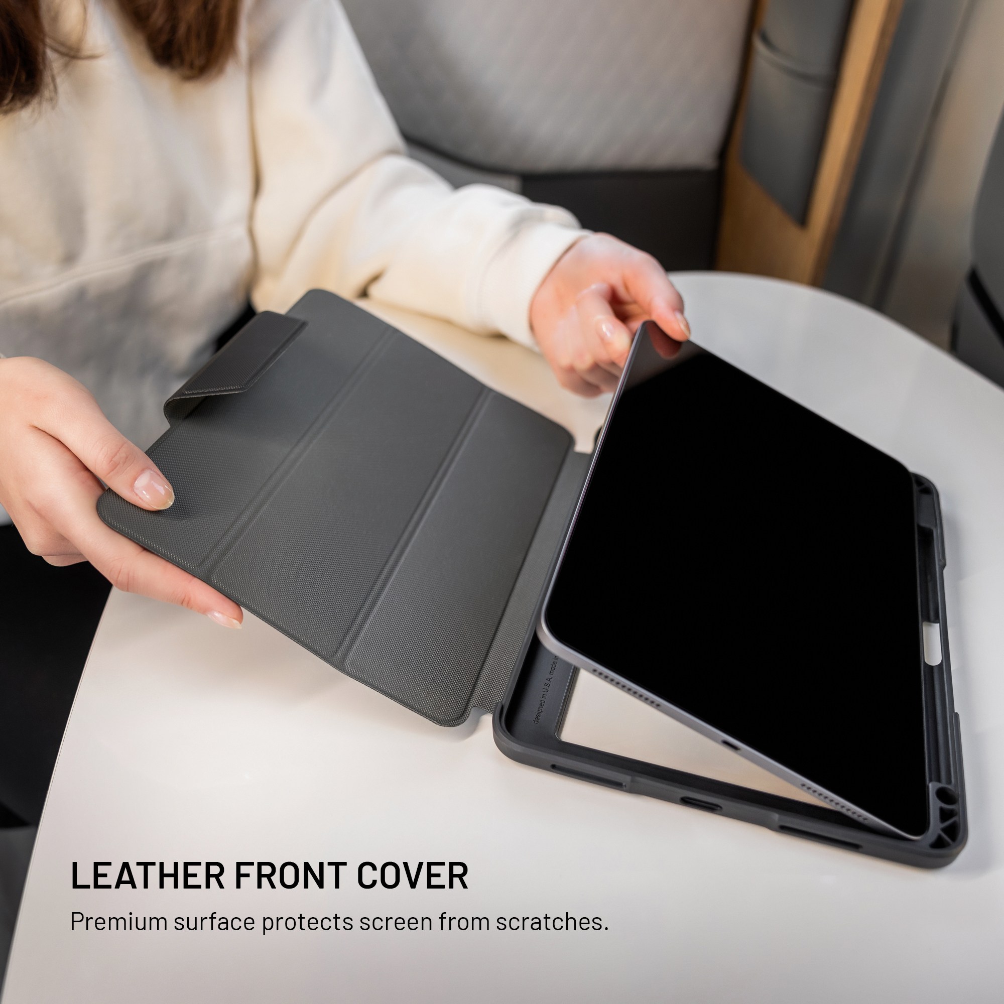 Person setzt ein Tablet in eine dunkle Schutzhülle mit Ledervorderseite ein.