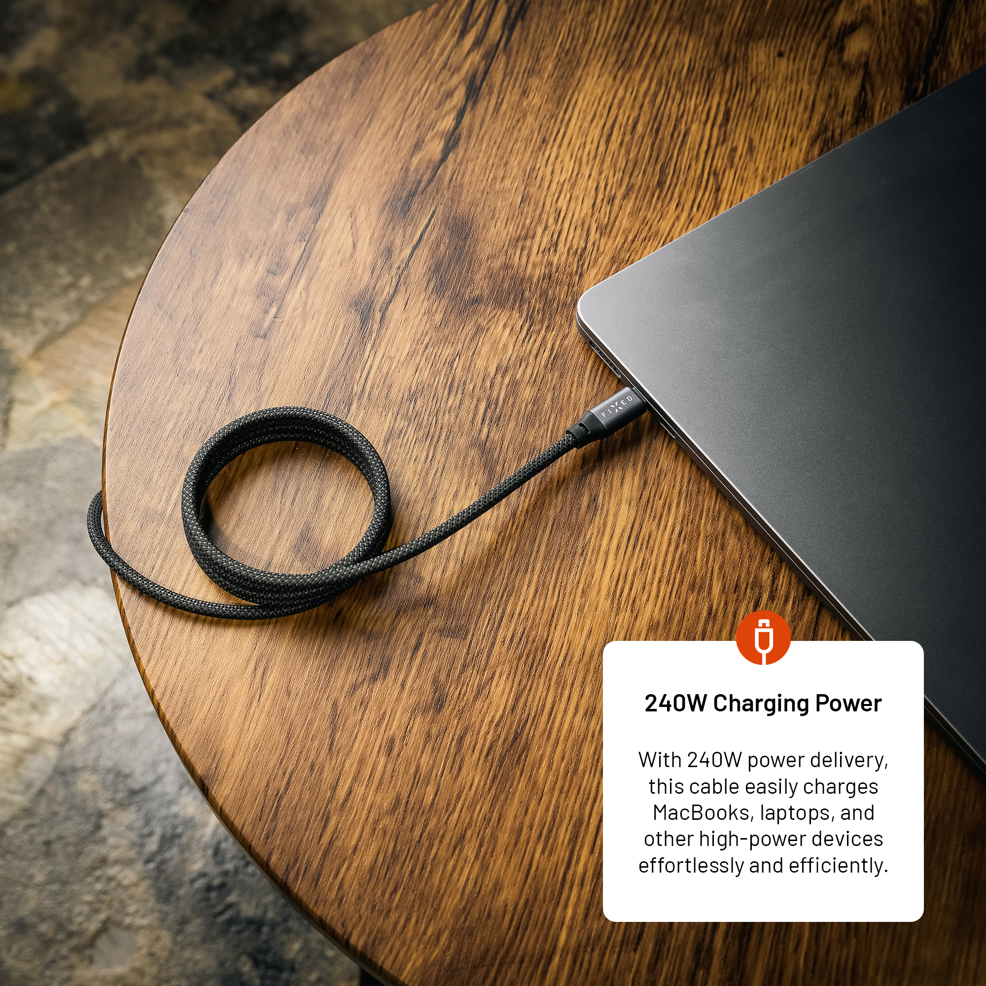 Ein schwarzes Ladekabel ist an einen Laptop auf einem Holztisch angeschlossen, mit Textfeld.