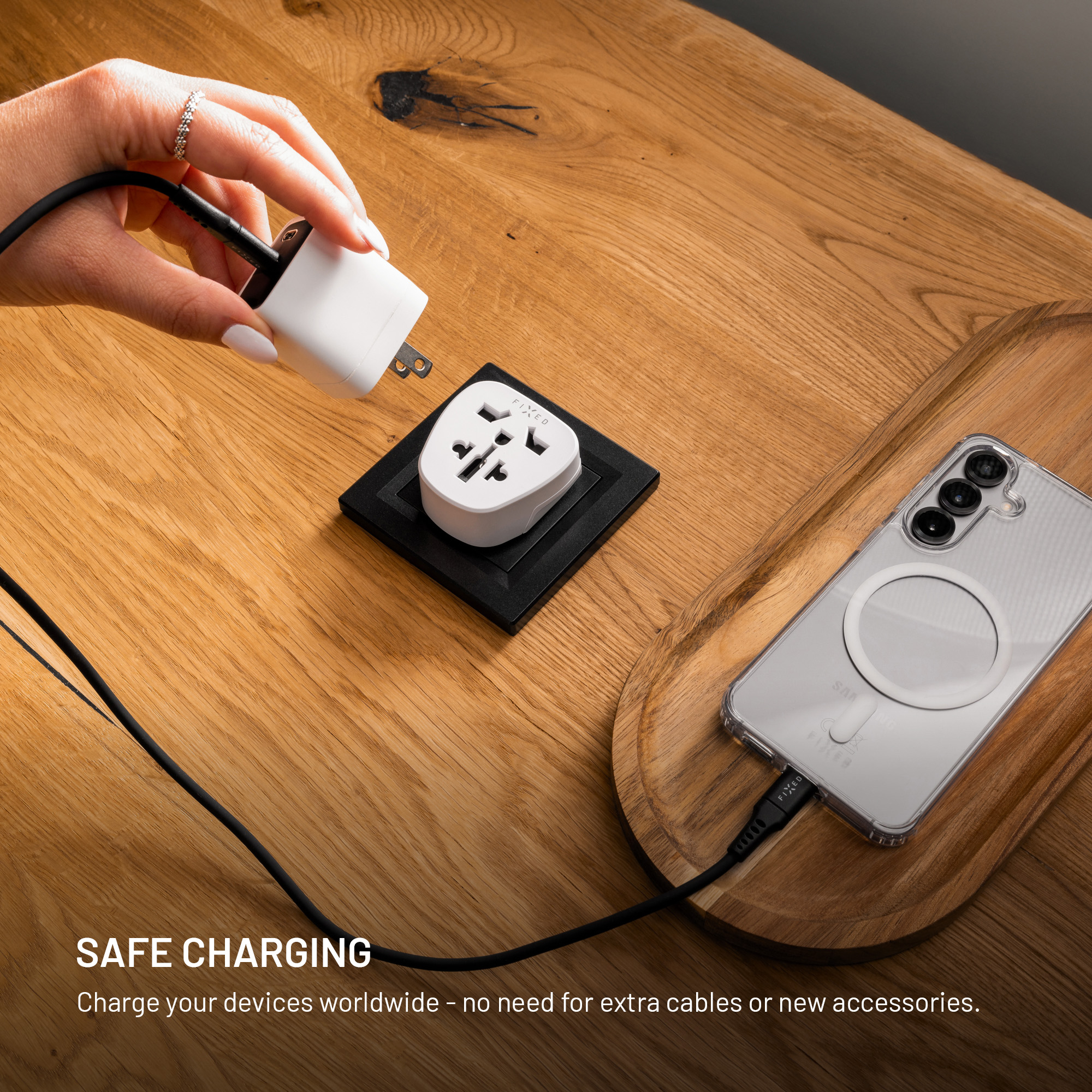 Hand hält weißes Ladegerät über Stecker auf Holzbrett neben angeschlossenem Smartphone.