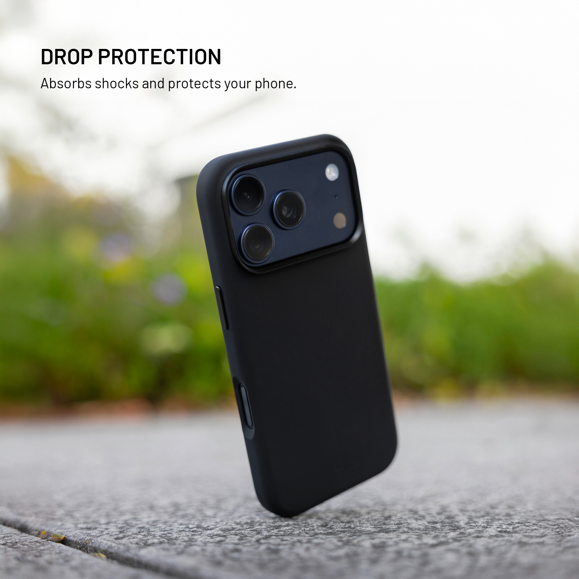 Ein schwarzes Smartphone in einer Schutzhülle steht auf einer grauen Betonoberfläche im Freien.