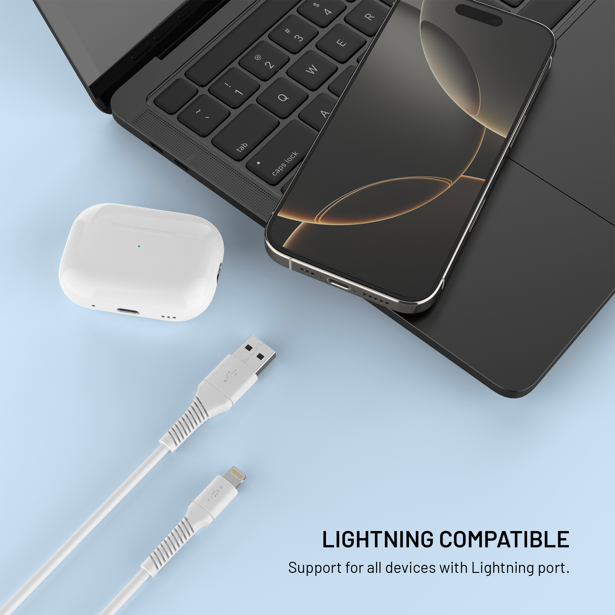 Smartphone, Ohrhörer und USB-Kabel auf blauem Hintergrund neben einem Laptop.