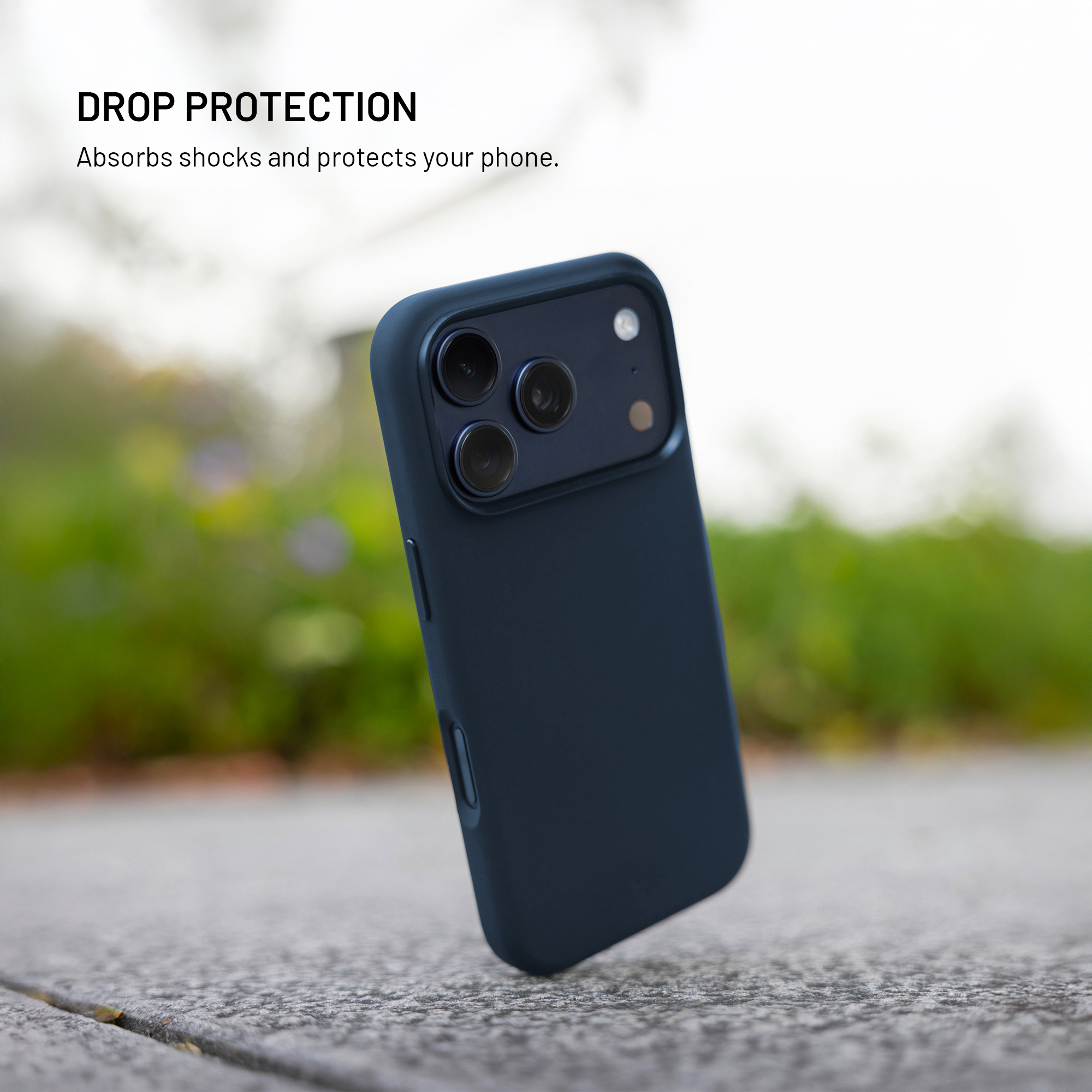 Ein dunkelblaues Smartphone in einer Schutzhülle steht leicht schräg auf einer Betonoberfläche im Freien.